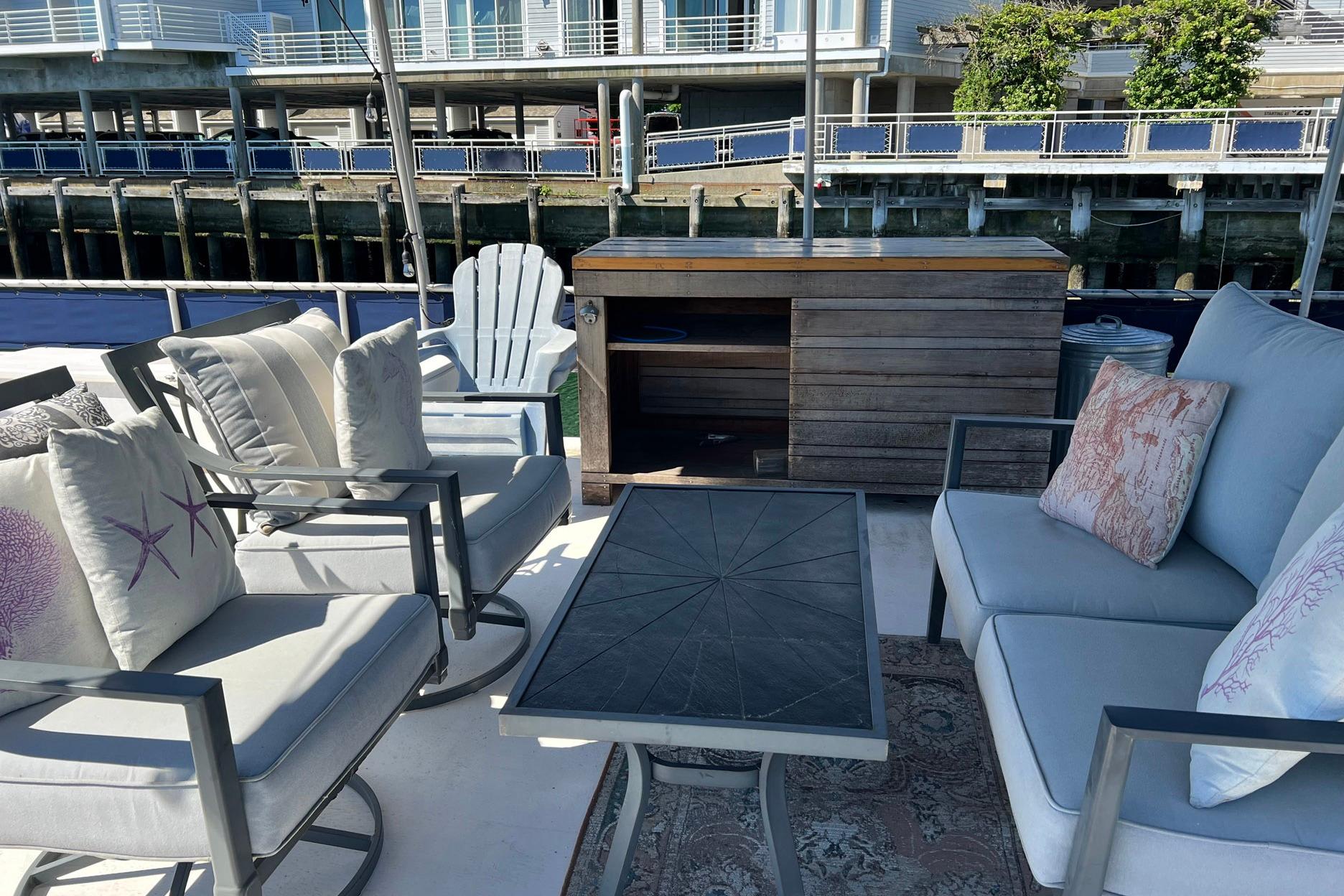 Cozy outdoor seating on a 1993 Sumerset houseboat with stylish cushions and a wooden cabinet.