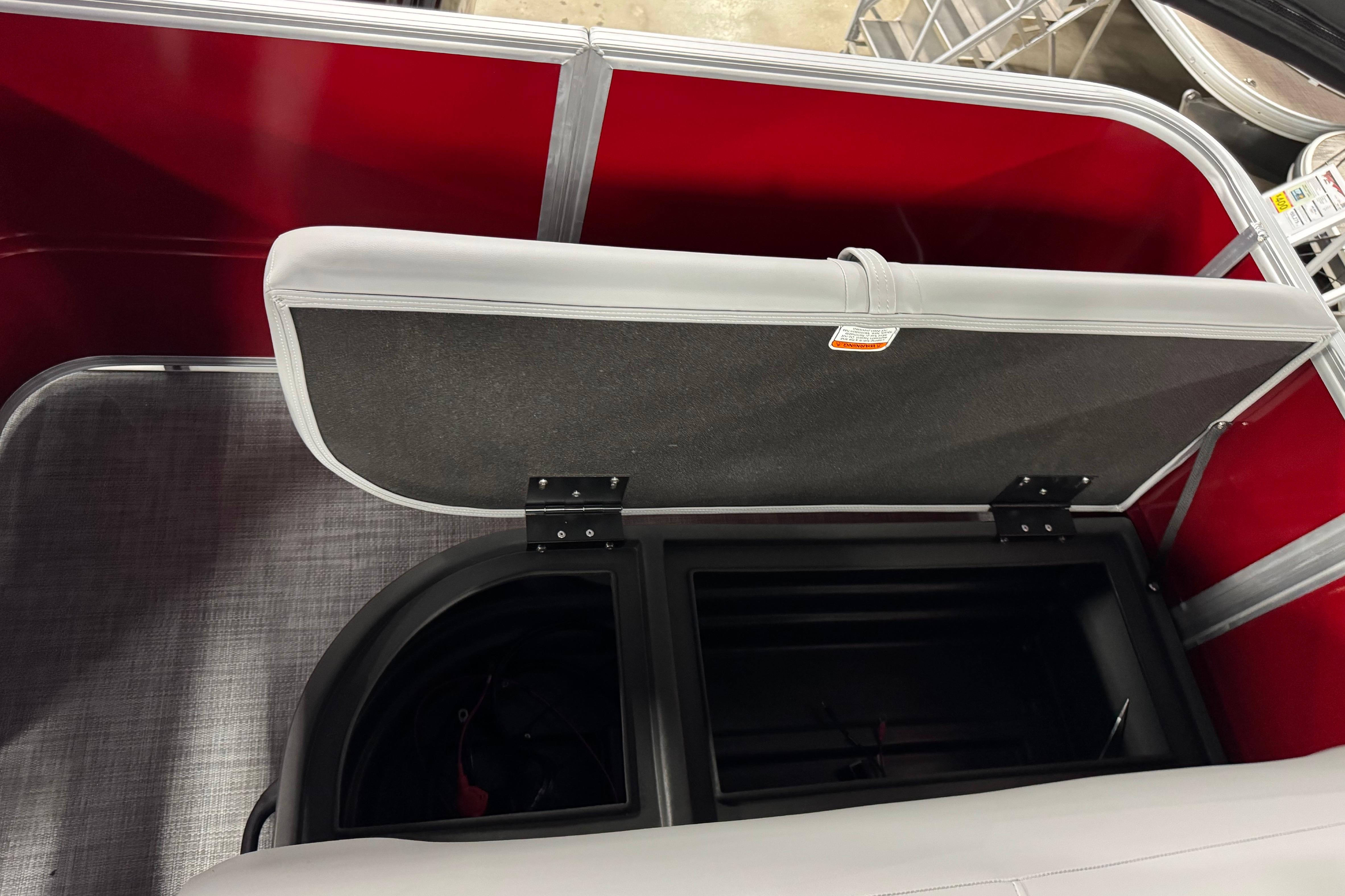 2026 Sun Tracker Party Barge 18 DLX storage compartment with open seat and red interior.