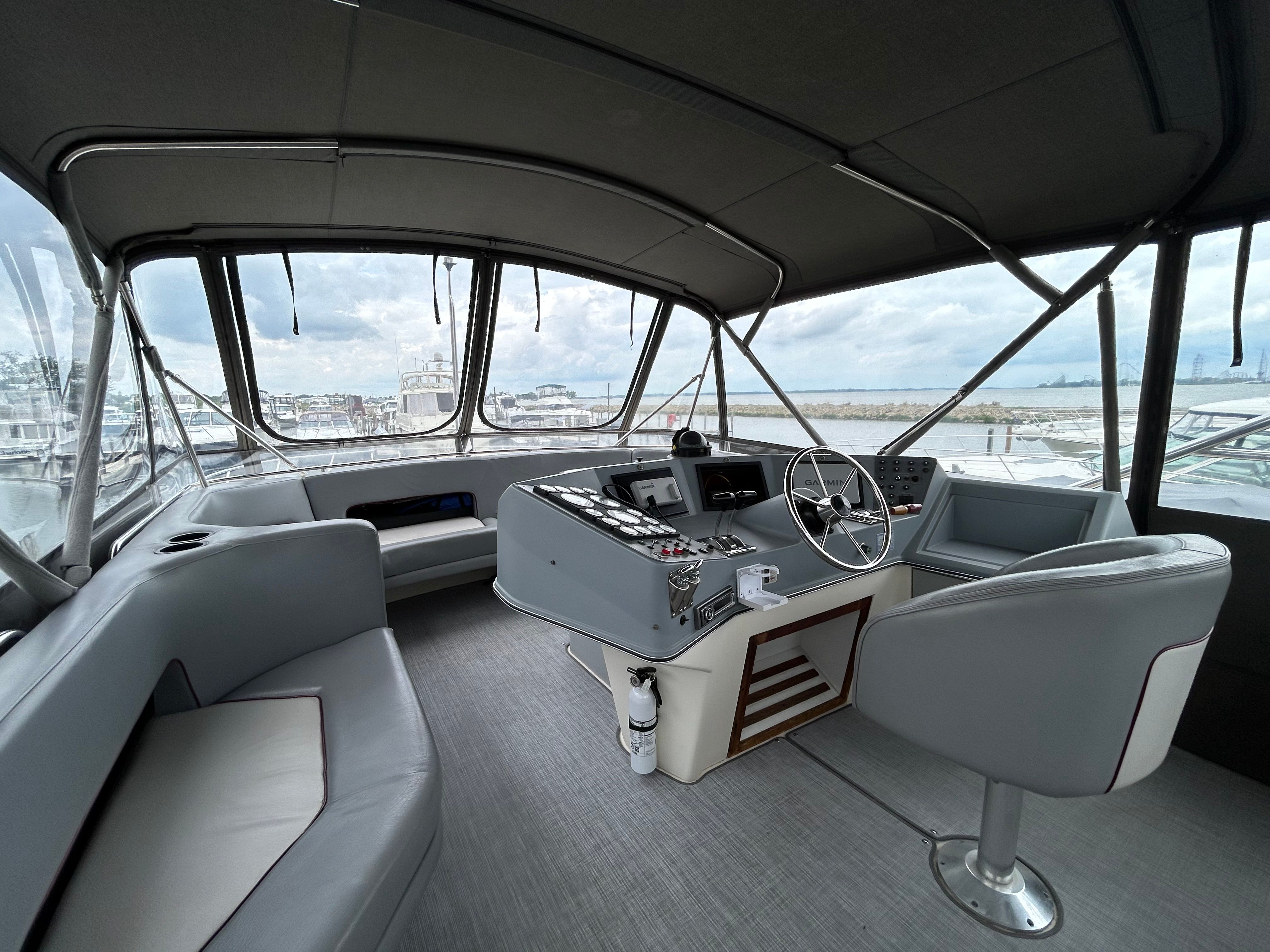 The image shows the cockpit of a 1988 Cruisers Yachts 4280 Express Bridge with gray seating.