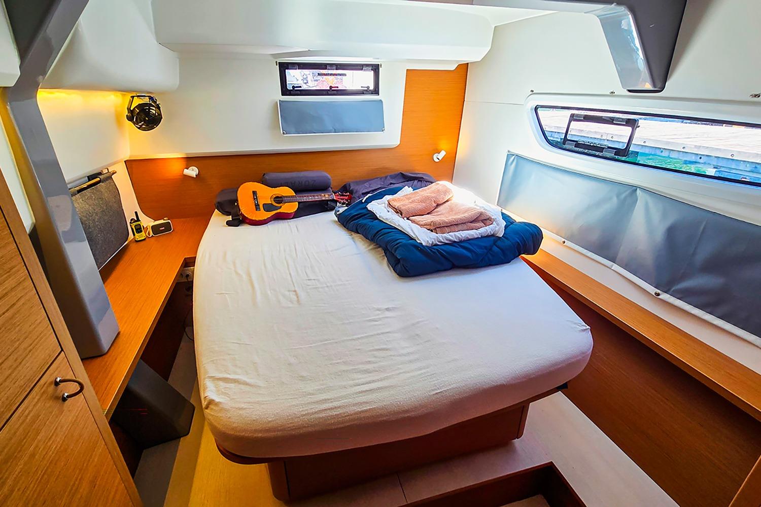 Cozy cabin interior of 2024 Excess 14 Pulse Line yacht with bed and guitar.