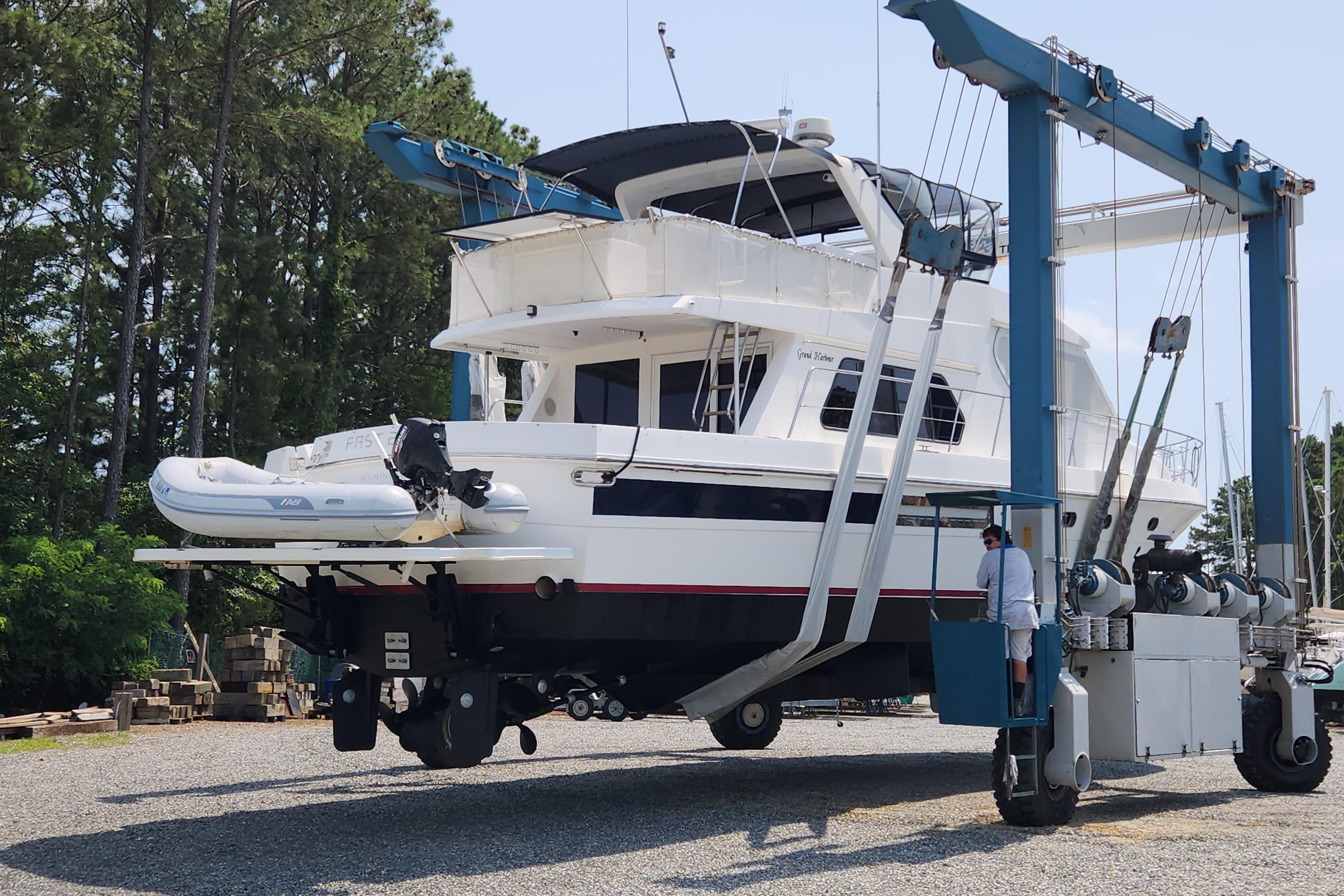 Grand Harbour 58 yacht from 2004 being lifted by a boat hoist in a marina.