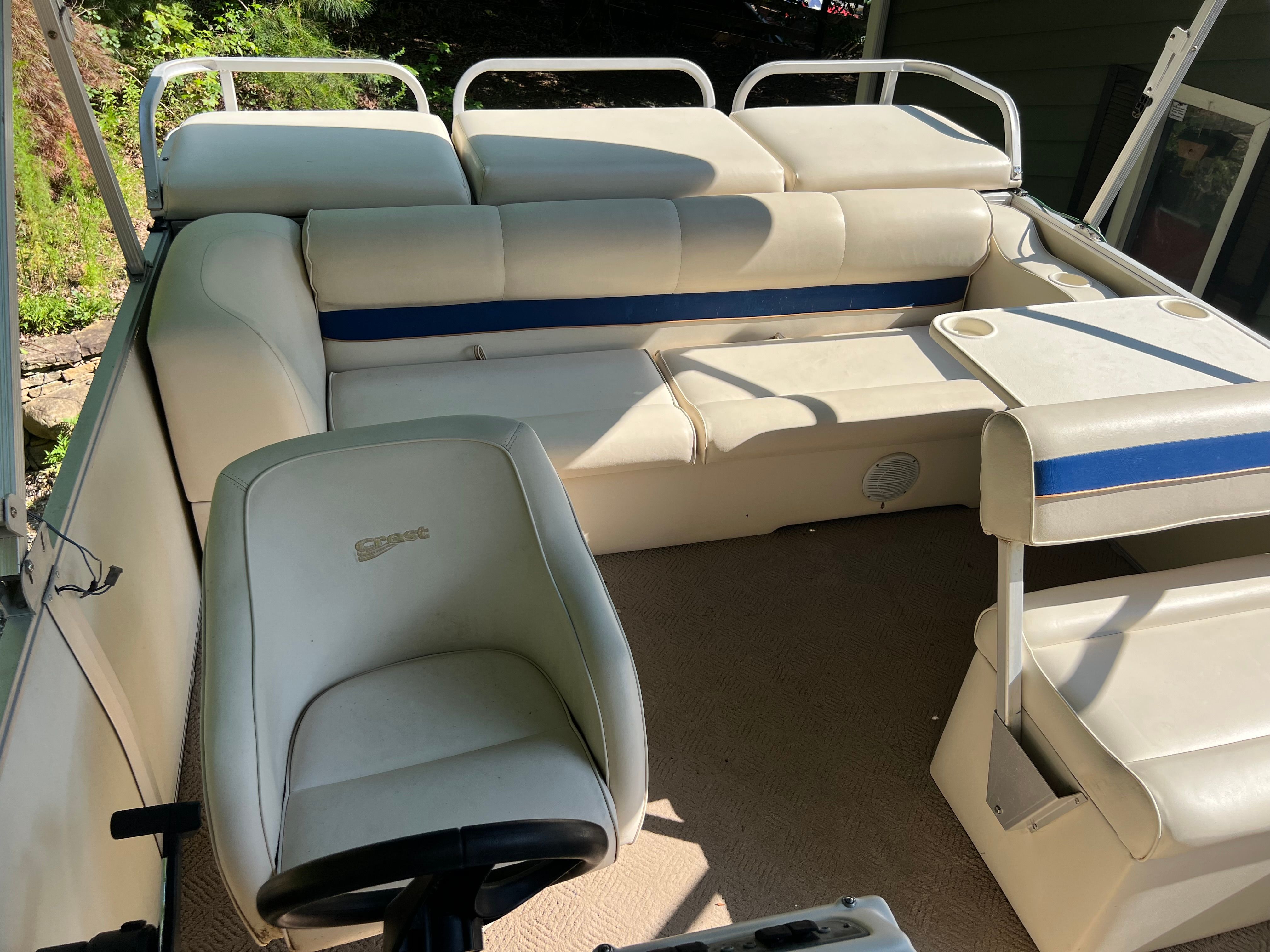Interior of a 2003 Crest 24’ Sport pontoon boat with white upholstery and blue accents.