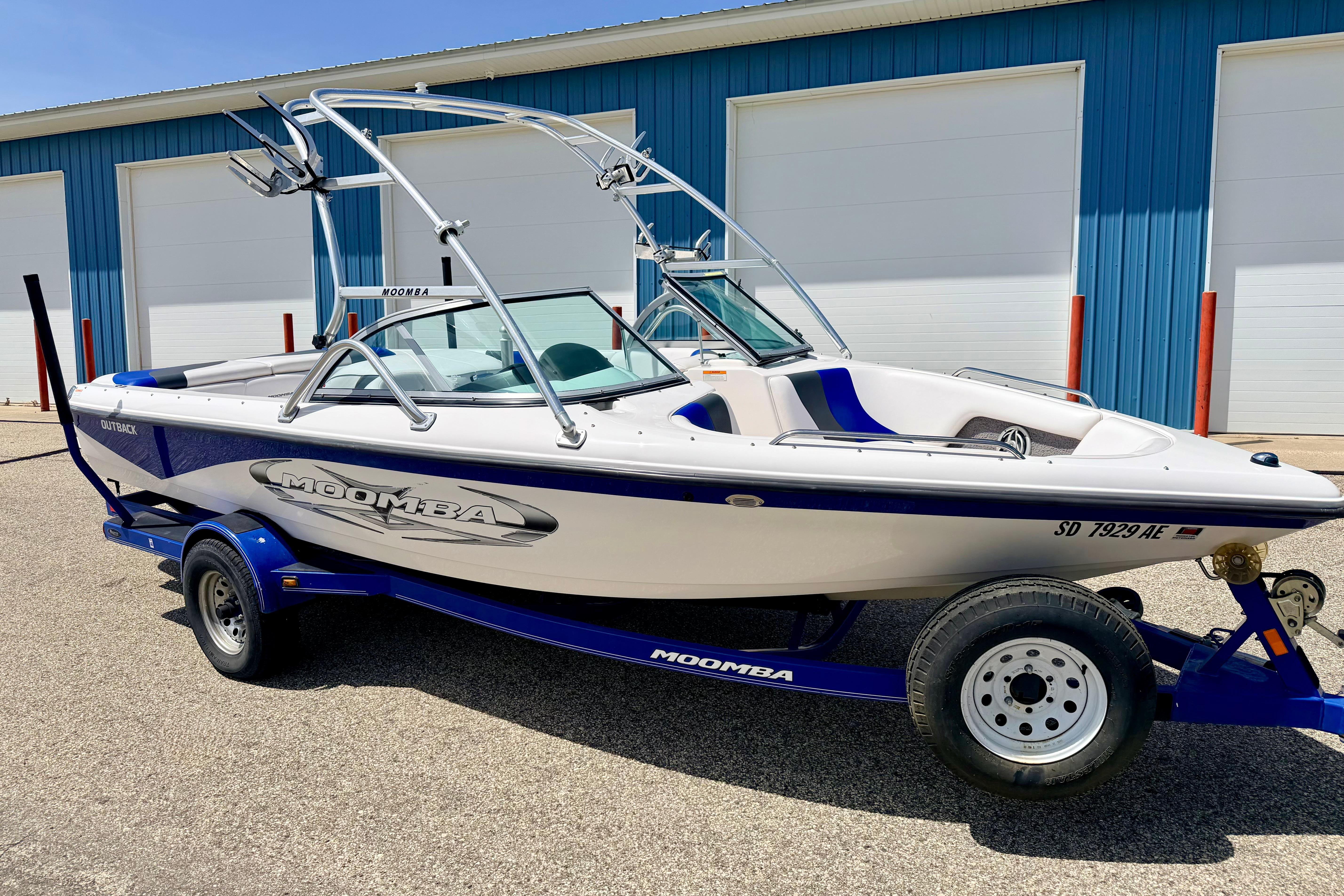2008 Moomba Outback V boat on trailer, parked near blue warehouse.
