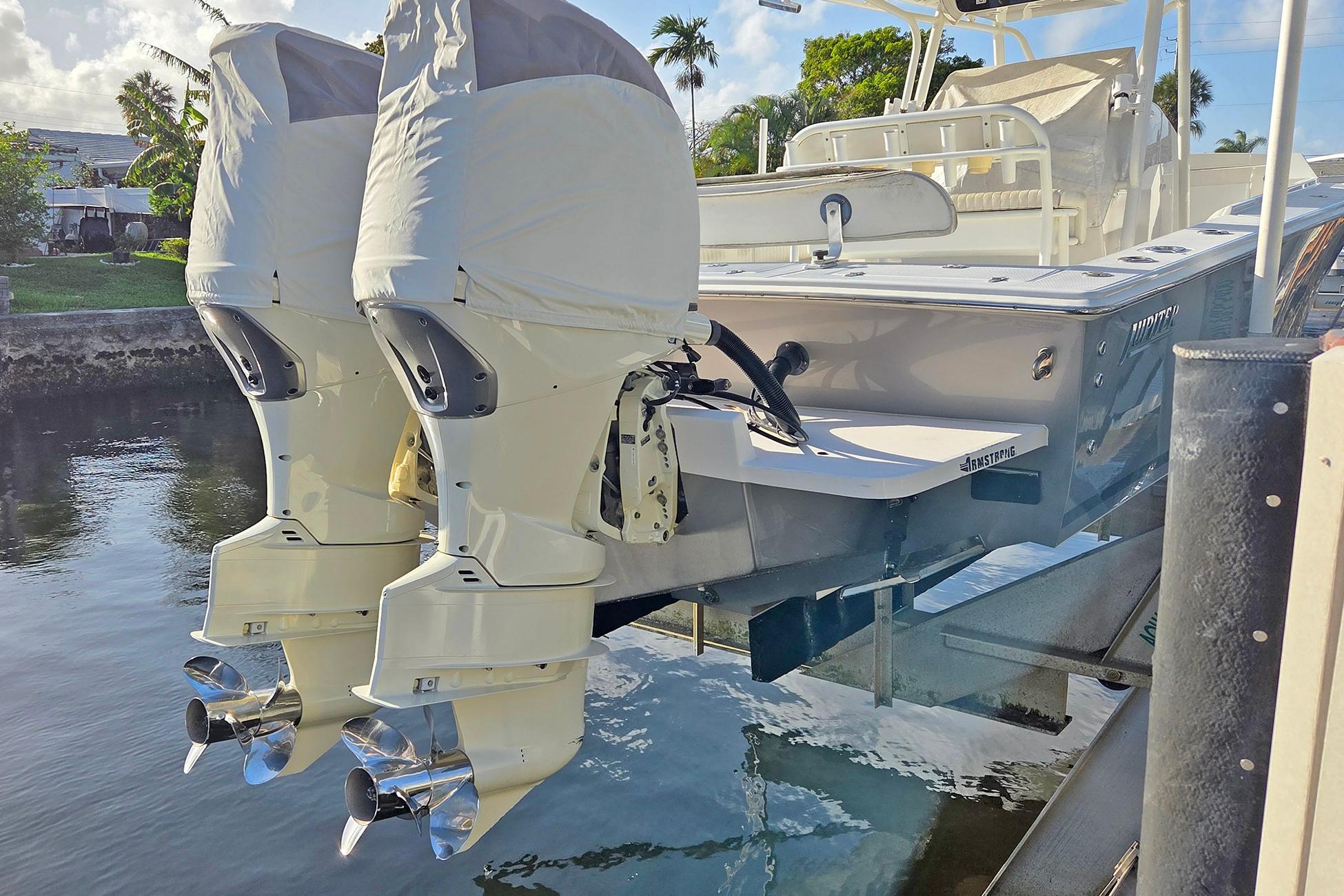 2001 Jupiter 31 Cuddy boat with twin outboard engines, docked by the water.