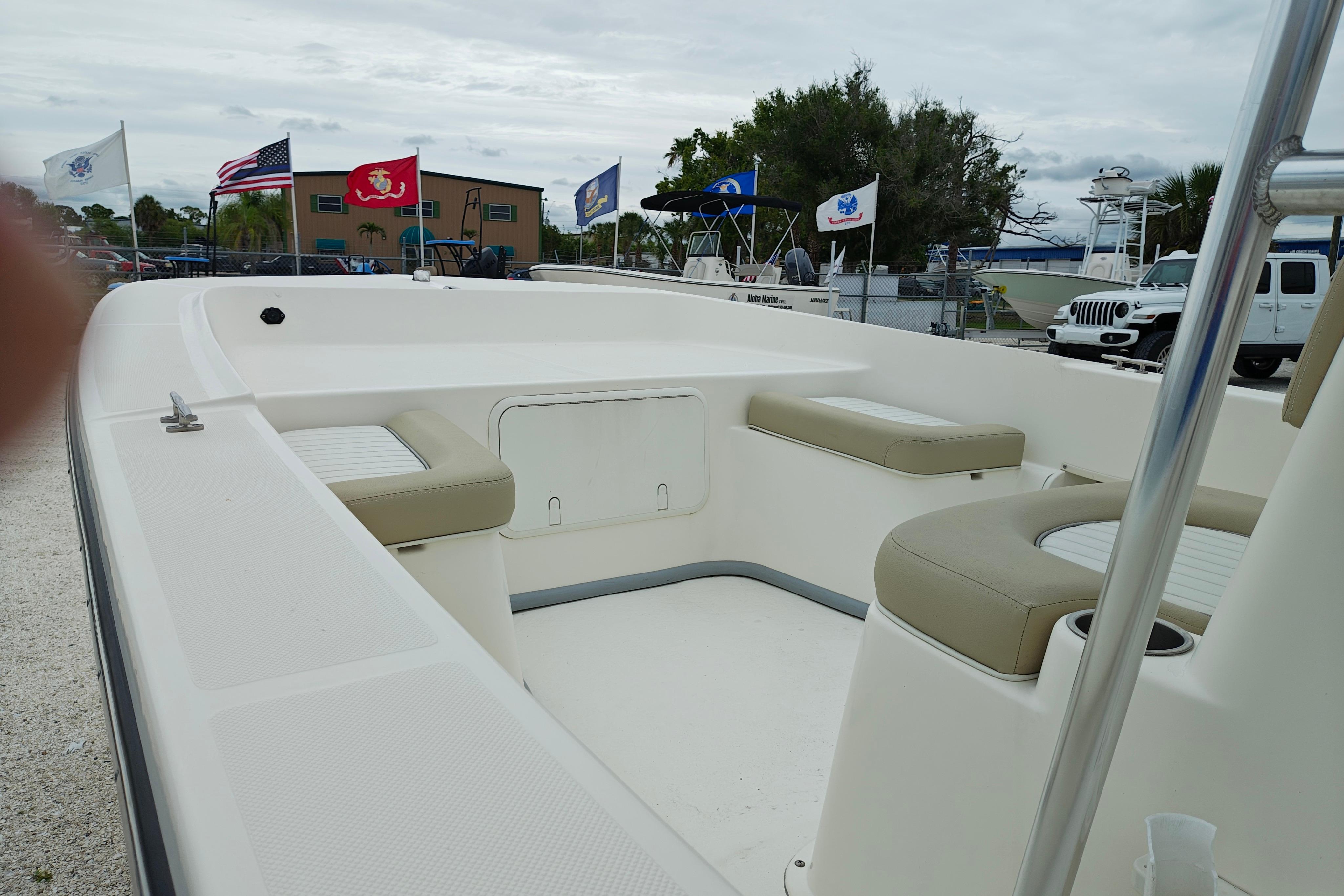 2018 Sundance B20CCR boat with beige seating, displayed outdoors with flags in the background.
