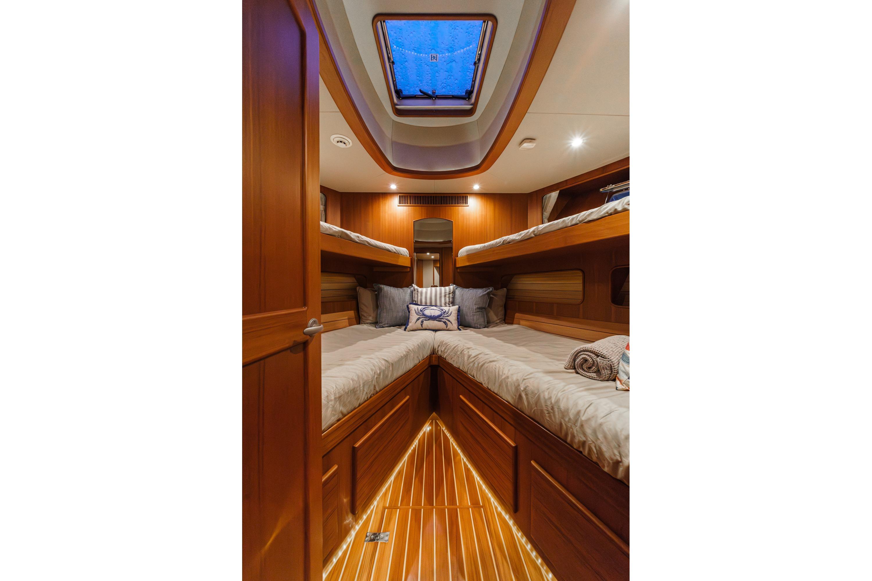 Luxurious cabin interior of 2018 Fleming 58 Pilothouse yacht with wooden finishes and cozy bedding.