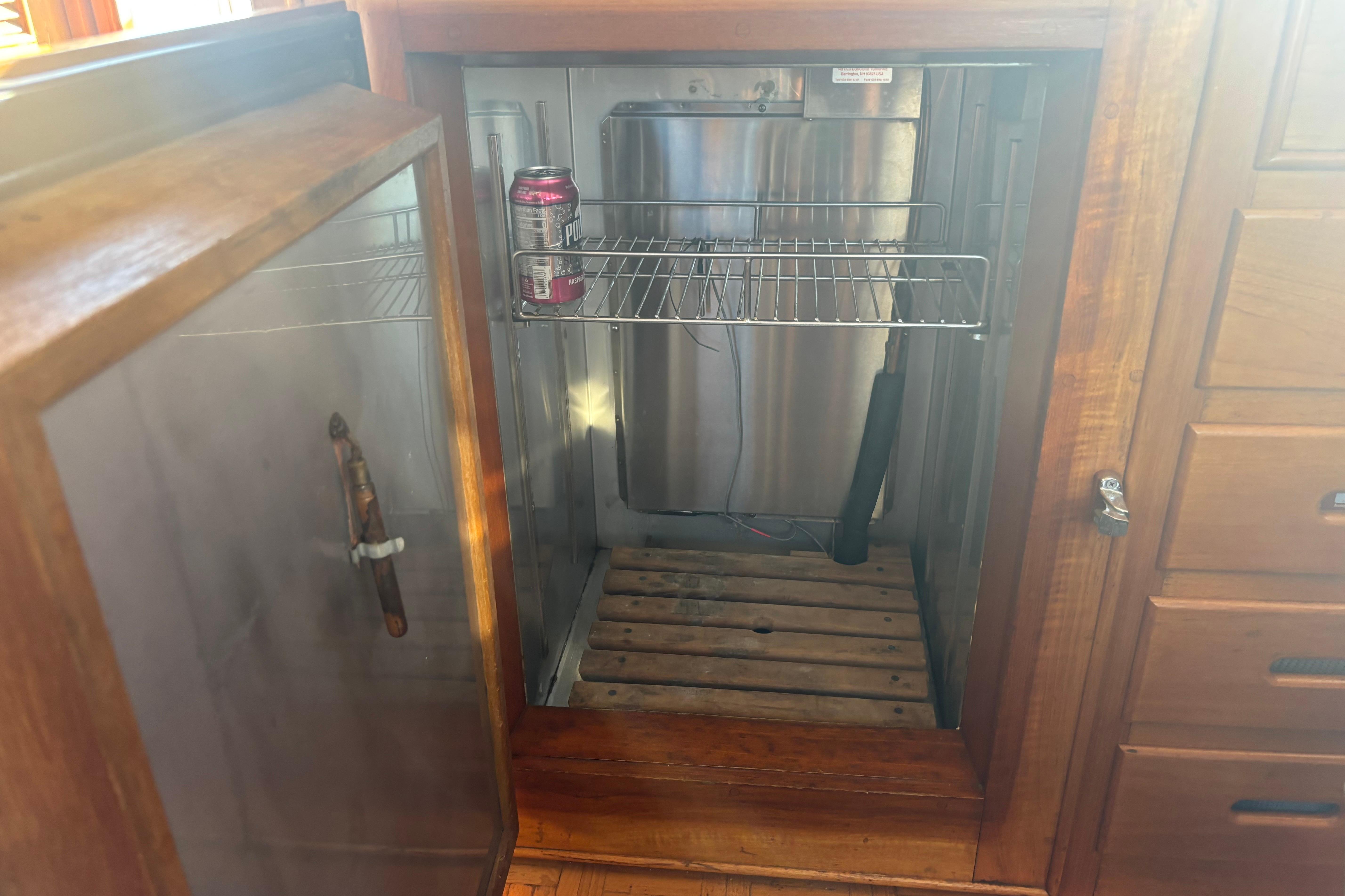 Open wooden cabinet with a single soda can inside, aboard a 1989 Grand Banks 46 Classic.