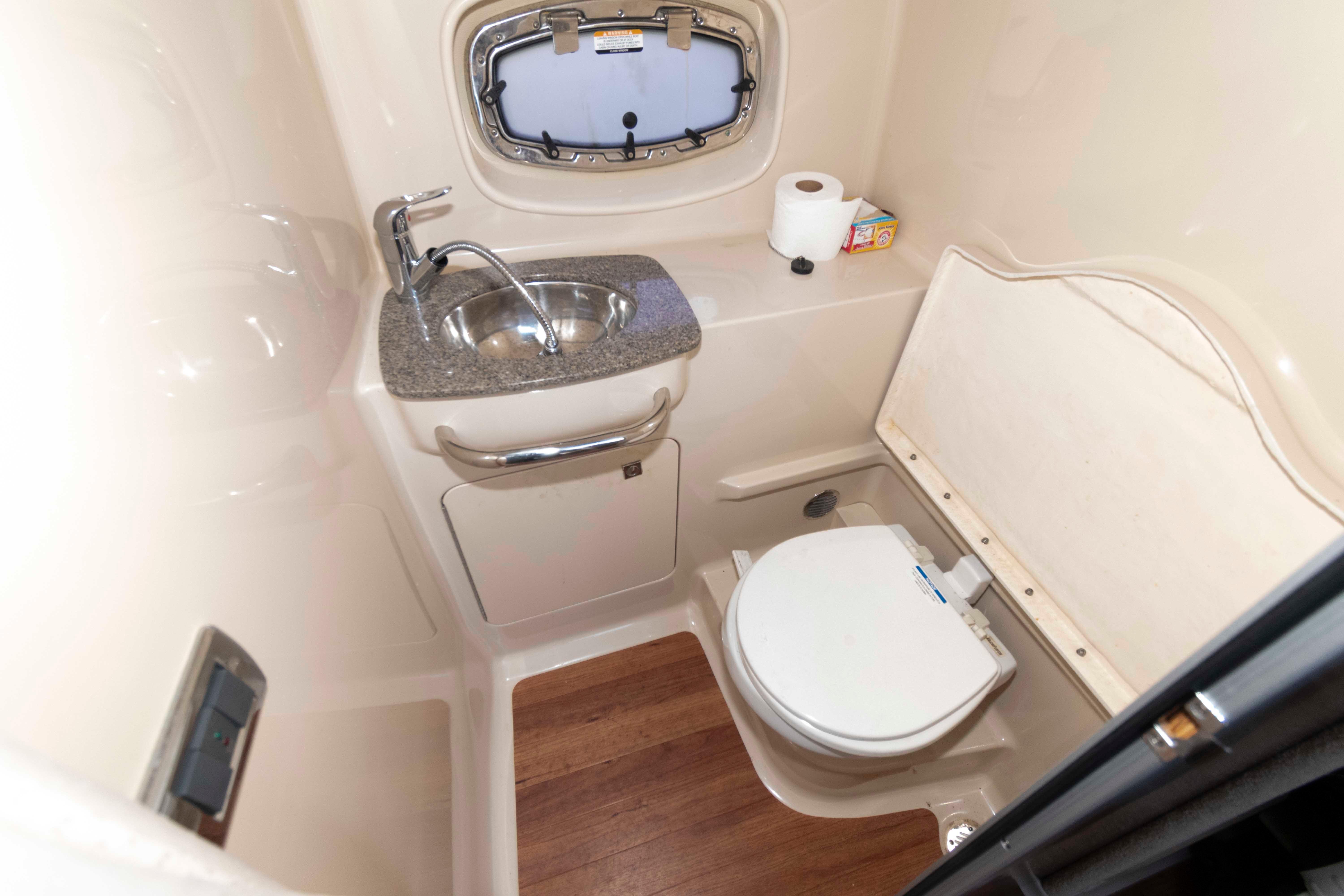 2013 Chaparral 310 Signature boat bathroom with sink, toilet, and wooden flooring.