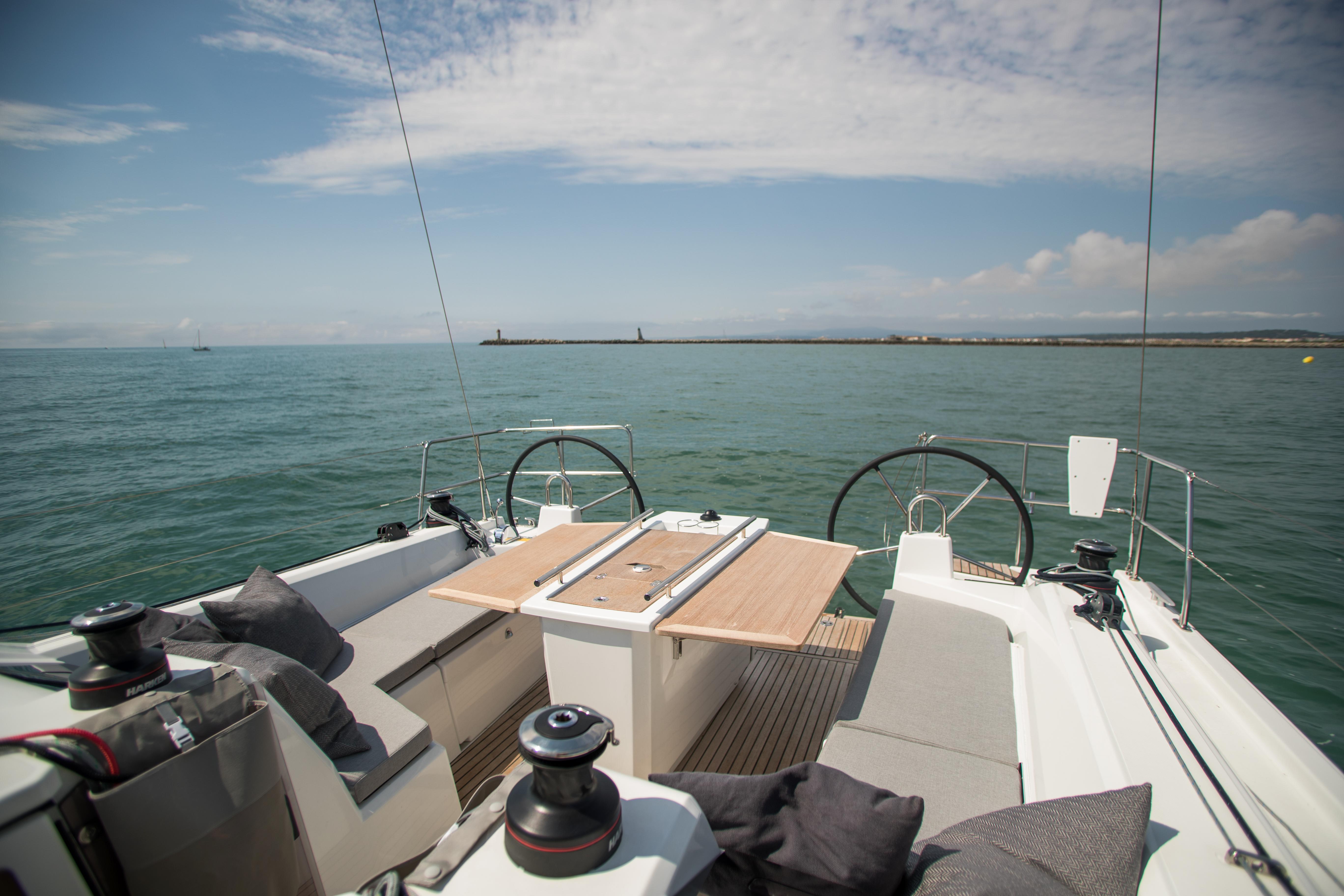 2025 Beneteau Oceanis 40.1 sailboat deck with dual steering wheels on calm sea.