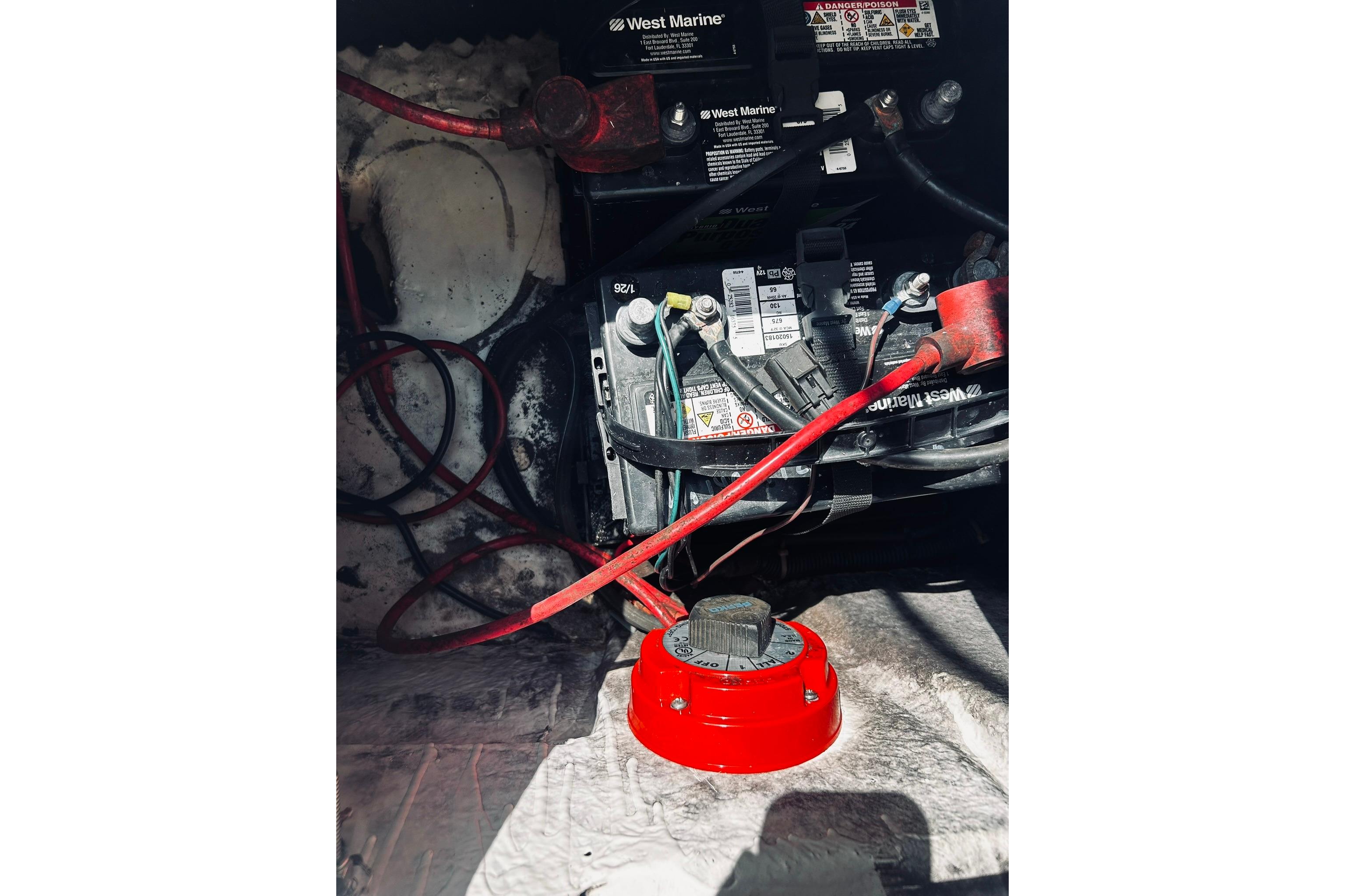 Battery compartment of 2013 Hurricane SunDeck Sport 201 OB with cables and red switch.