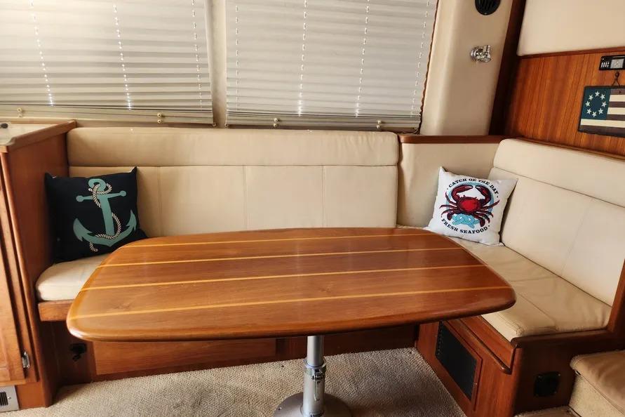 Cozy interior of a 2006 American Tug AT with nautical-themed cushions and wooden table.