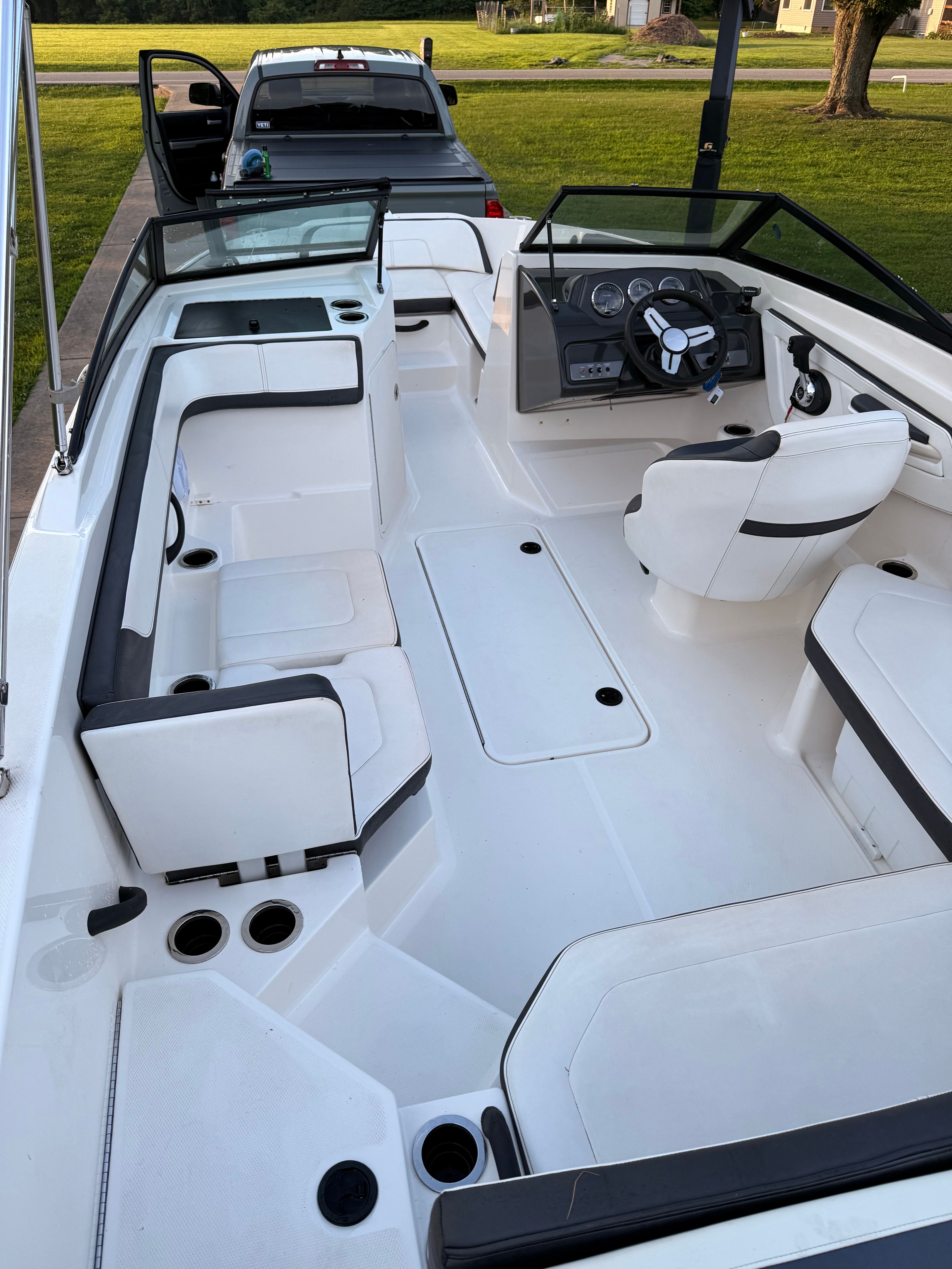 Interior view of a 2016 Sea Ray SPX 210 Outboard boat with white seating and black steering wheel.