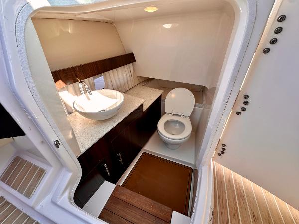 The image shows a sleek boat bathroom with a sink and toilet.