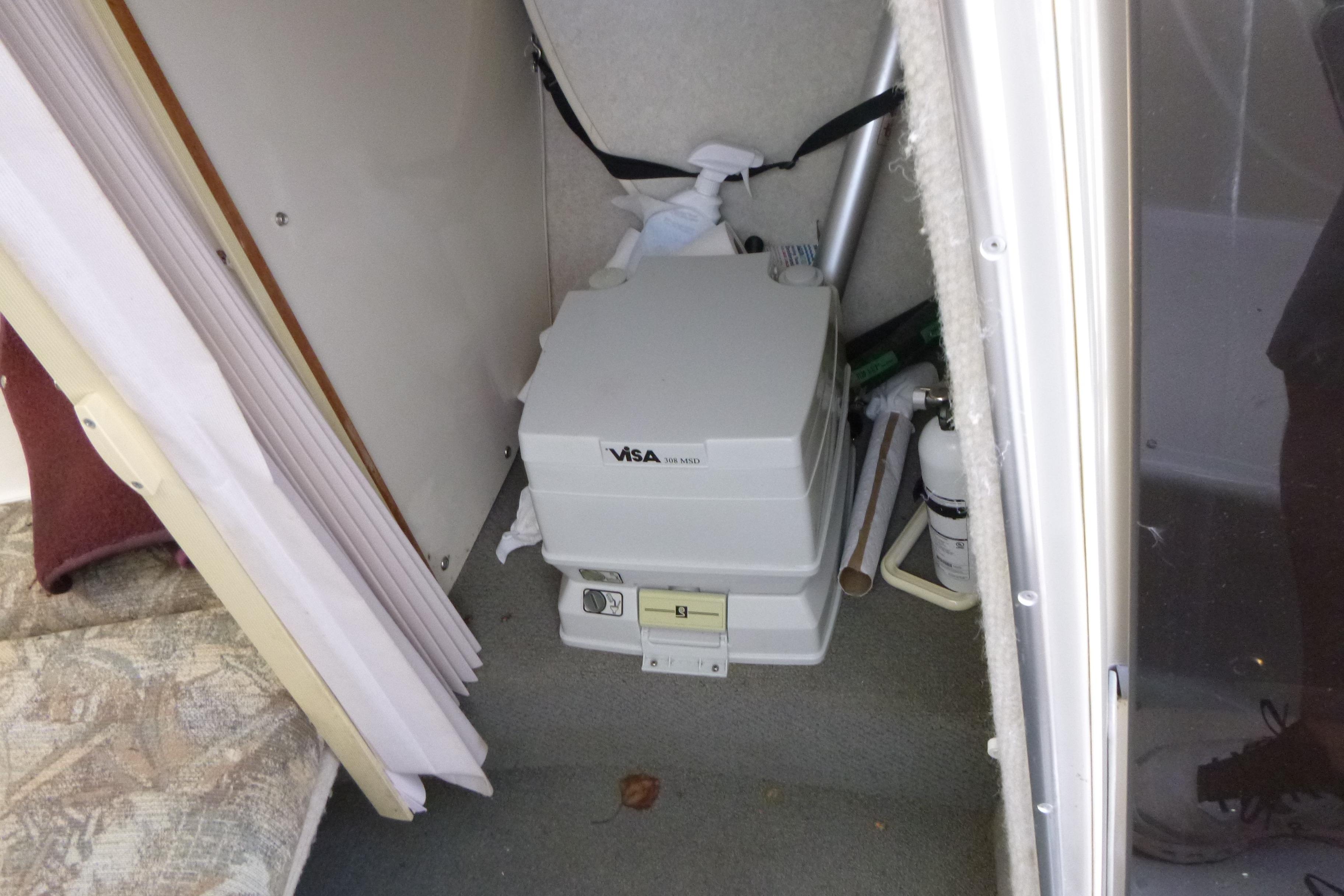 Portable toilet inside 1998 Maxum 2300 SC boat cabin.