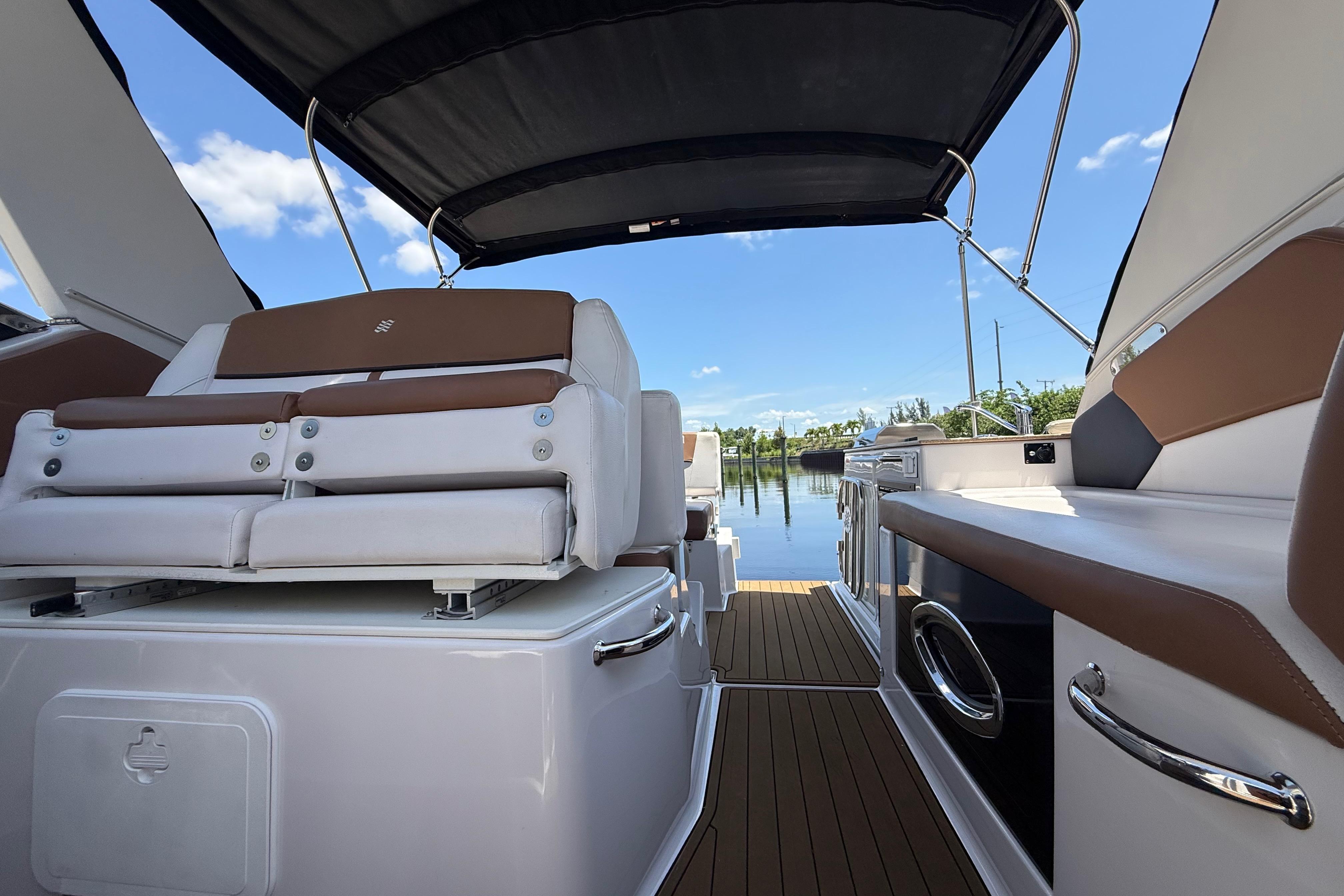 2017 Four Winns V275 boat interior with cushioned seating and canopy, docked by calm waters.