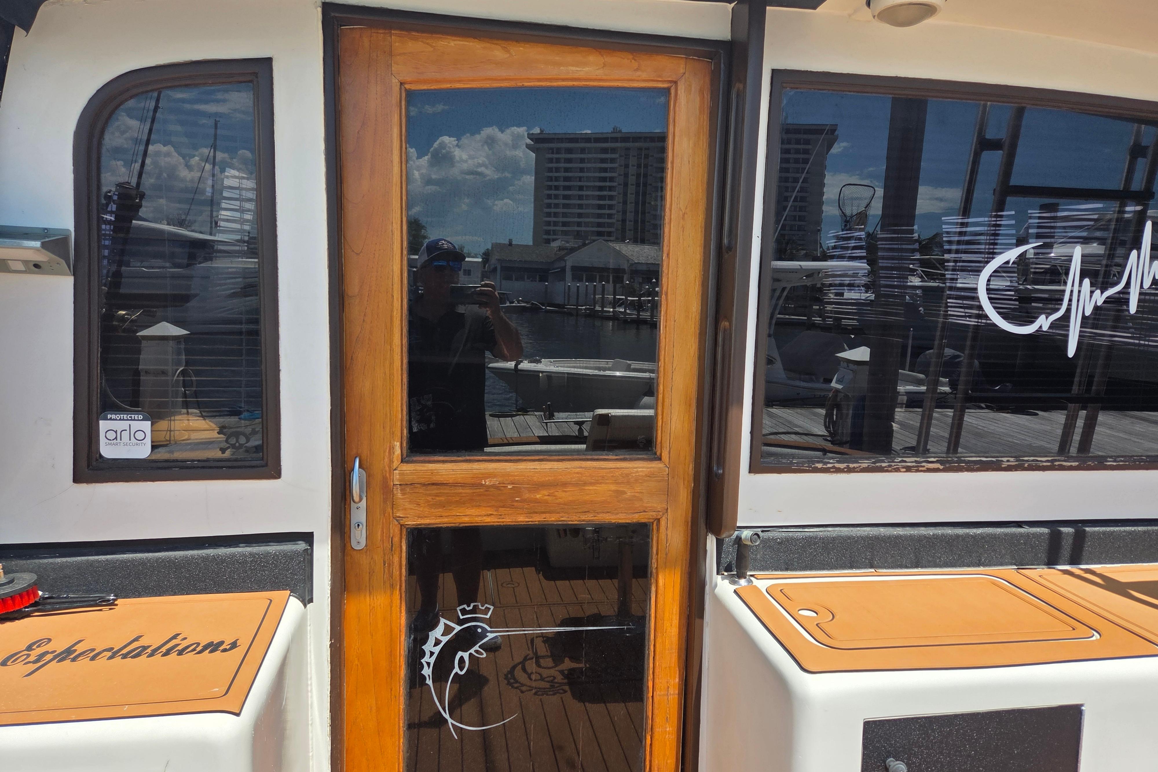 1990 Egg Harbor Golden Egg 42 yacht with wooden door and marina reflection.