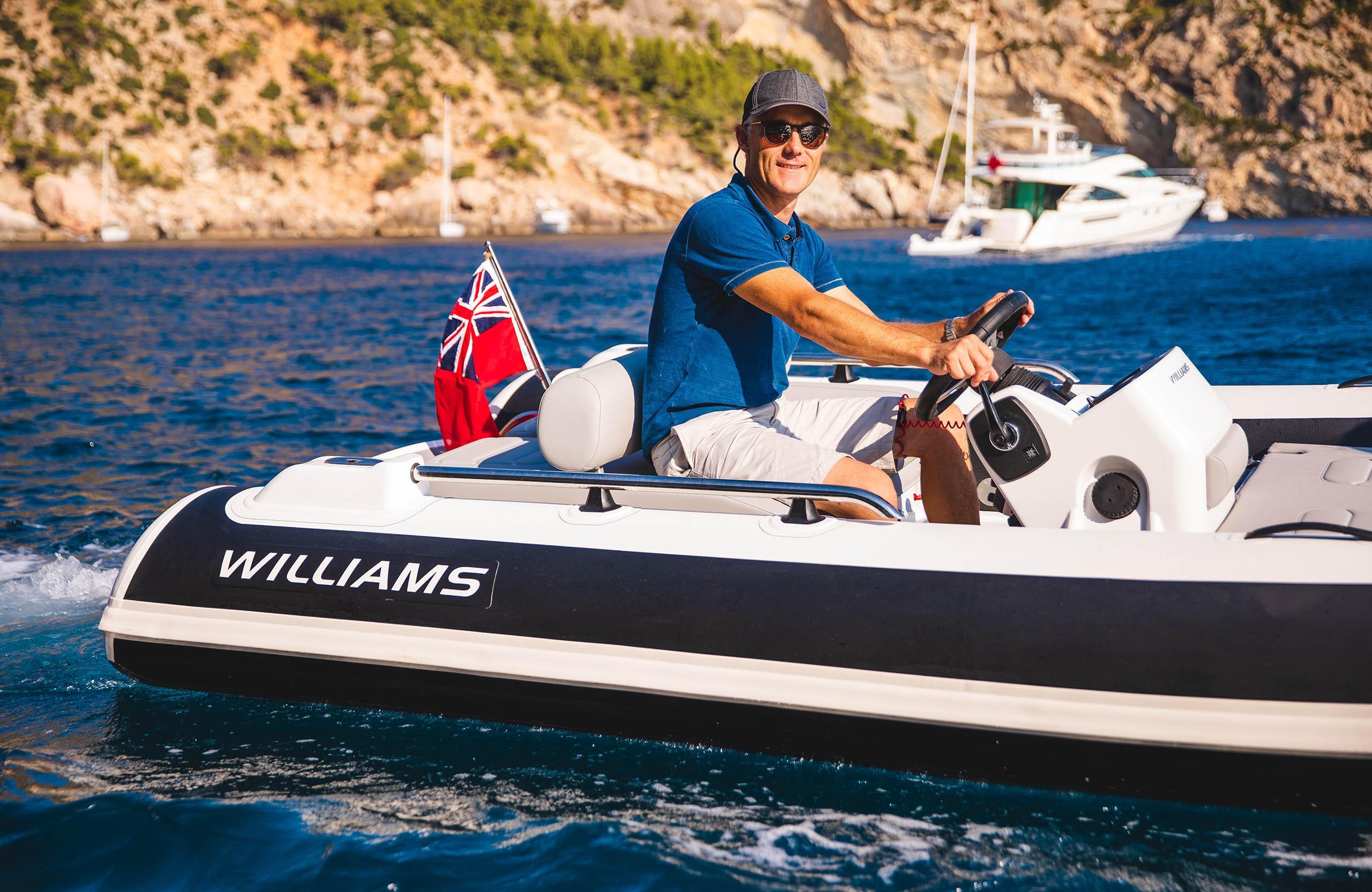 Man driving 2025 Williams Jet Tenders Sportjet 435 on blue water, scenic background.