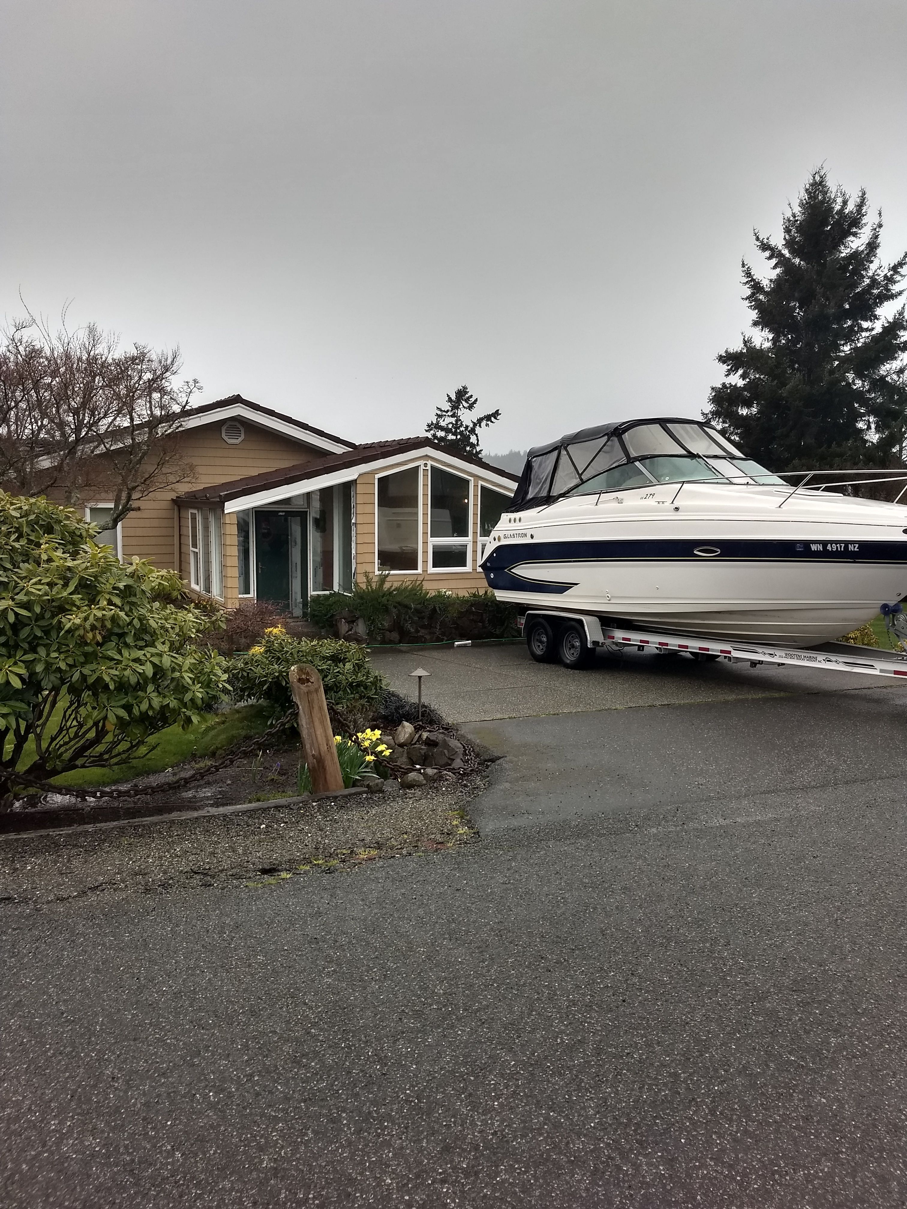 2006 Glastron GS boat on trailer parked in front of a house.