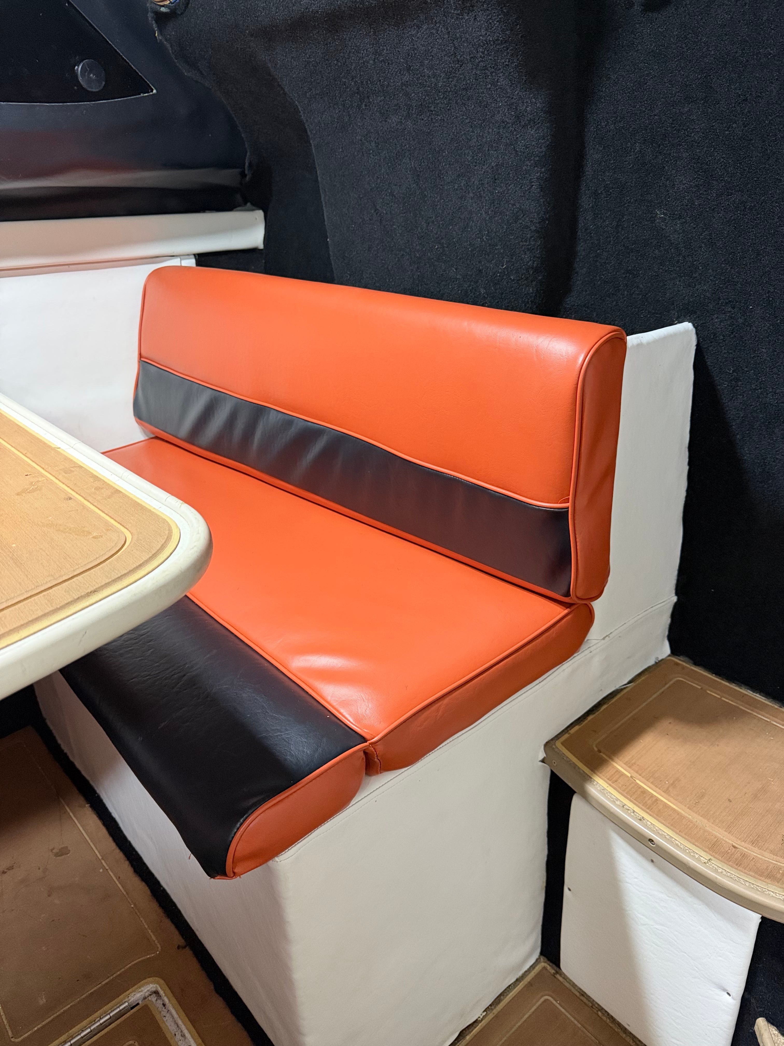 Interior of the Bayliner 2452 Ciera Classic with orange and black seating and a wooden table.