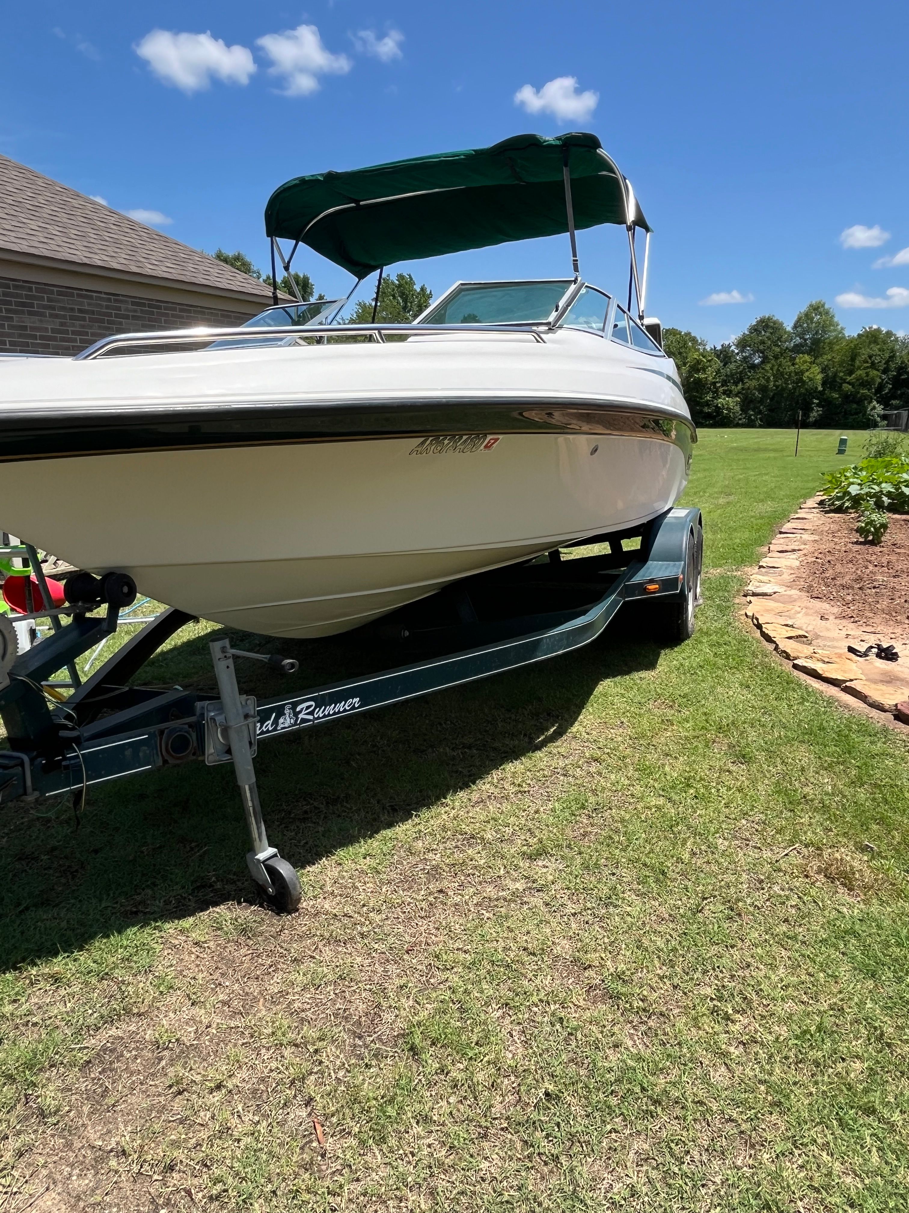 A 1996 Crownline 202 BR boat on a trailer, parked on a grassy area.