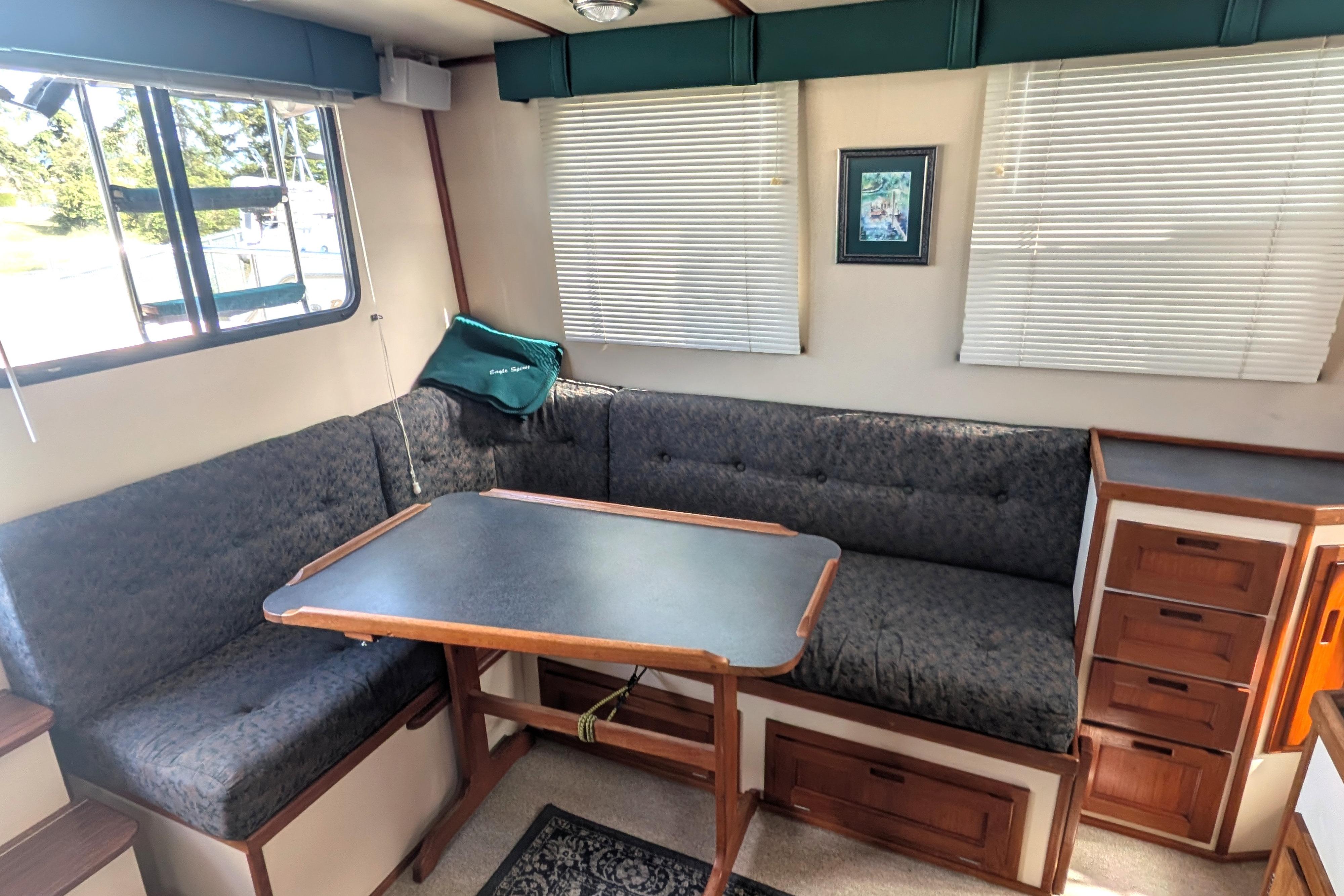 Cozy interior of a 1998 Nordic Tug 32 with a dining area and cushioned seating.