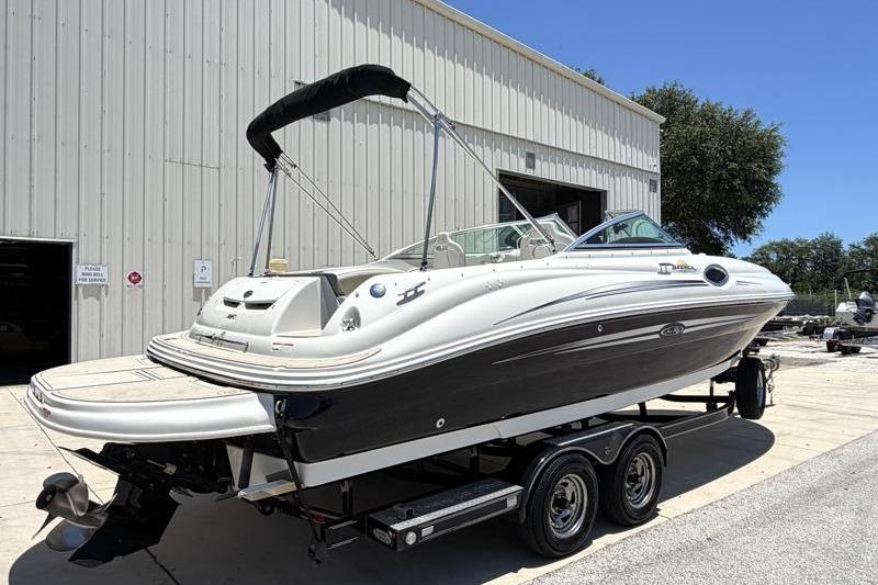 2007 Sea Ray 240 Sundeck boat on trailer, parked outside a large building.