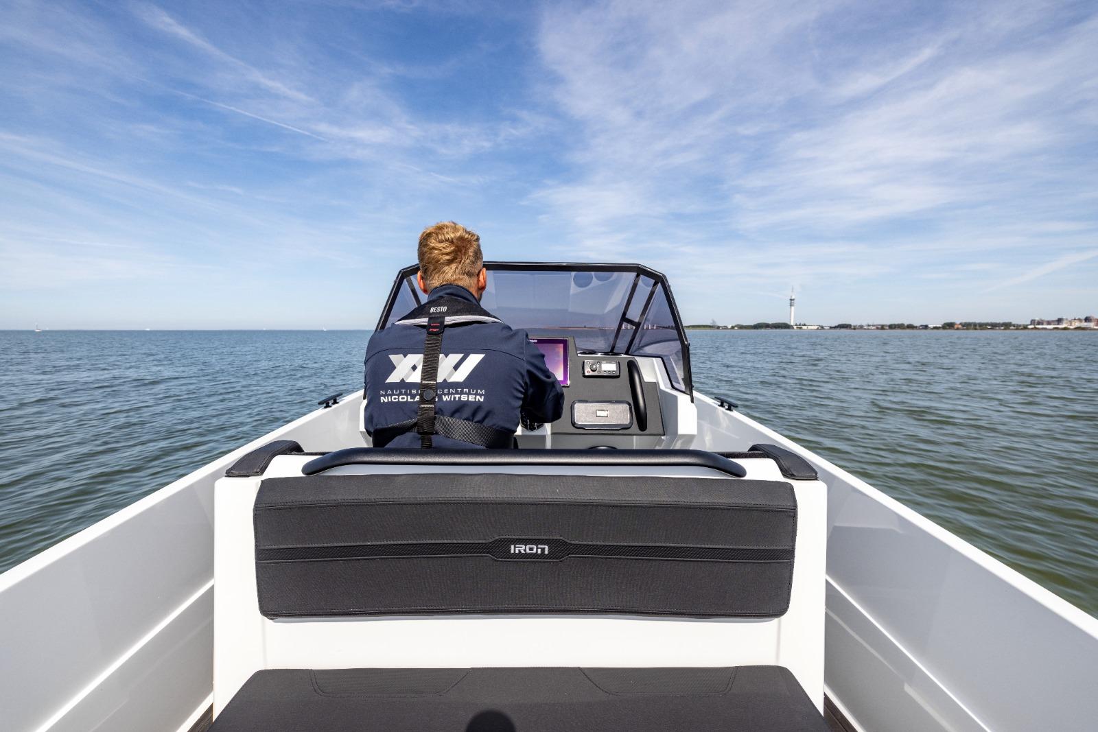 Man steering Iron 707 boat on open water, clear sky, 2022 model.