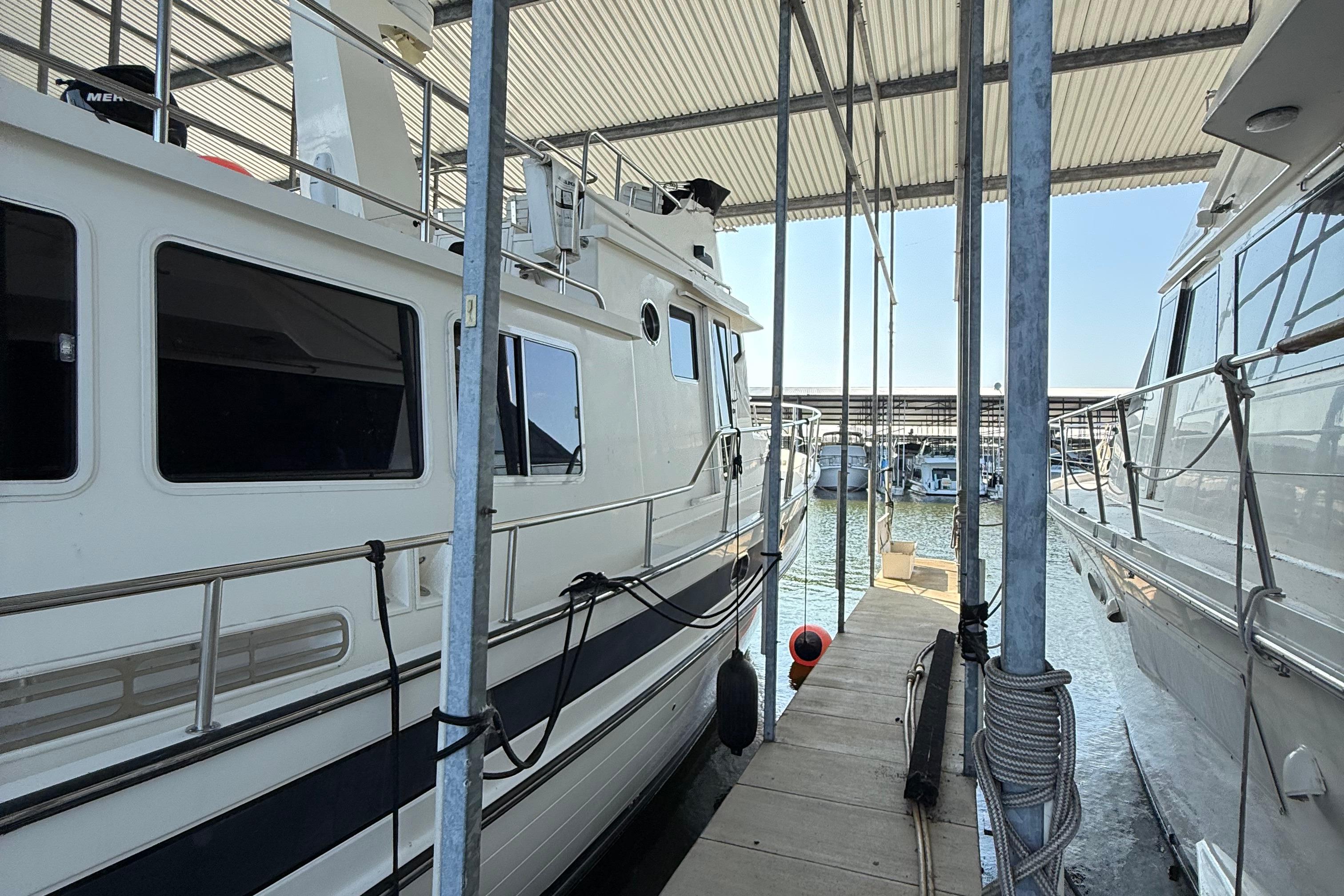 2007 Nordic Tug 54 docked in a marina, sheltered under a metal roof.