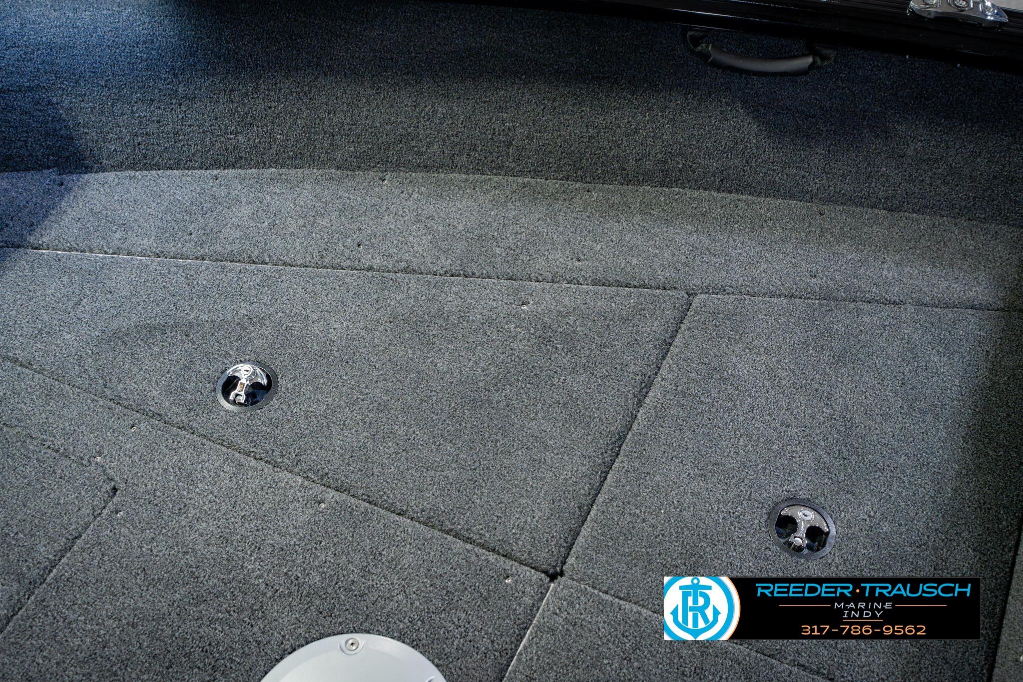 2026 Lund 1875 Impact XS boat interior with carpeted flooring and storage compartments.