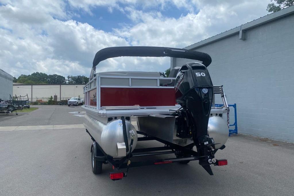 2026 Sun Tracker Bass Buggy 16 XL Select pontoon boat with outboard motor, parked outdoors.