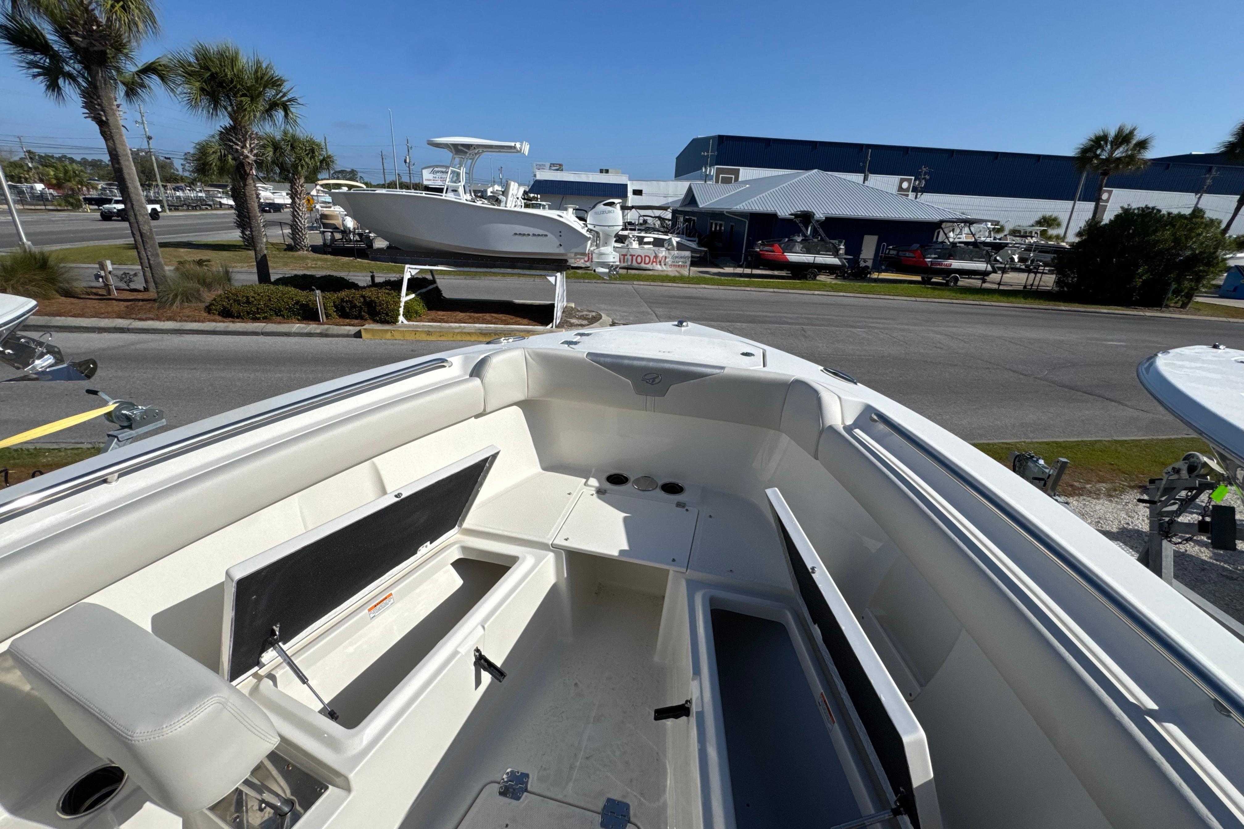 2026 Sailfish 272 CC boat interior with open storage compartments, docked near palm trees.