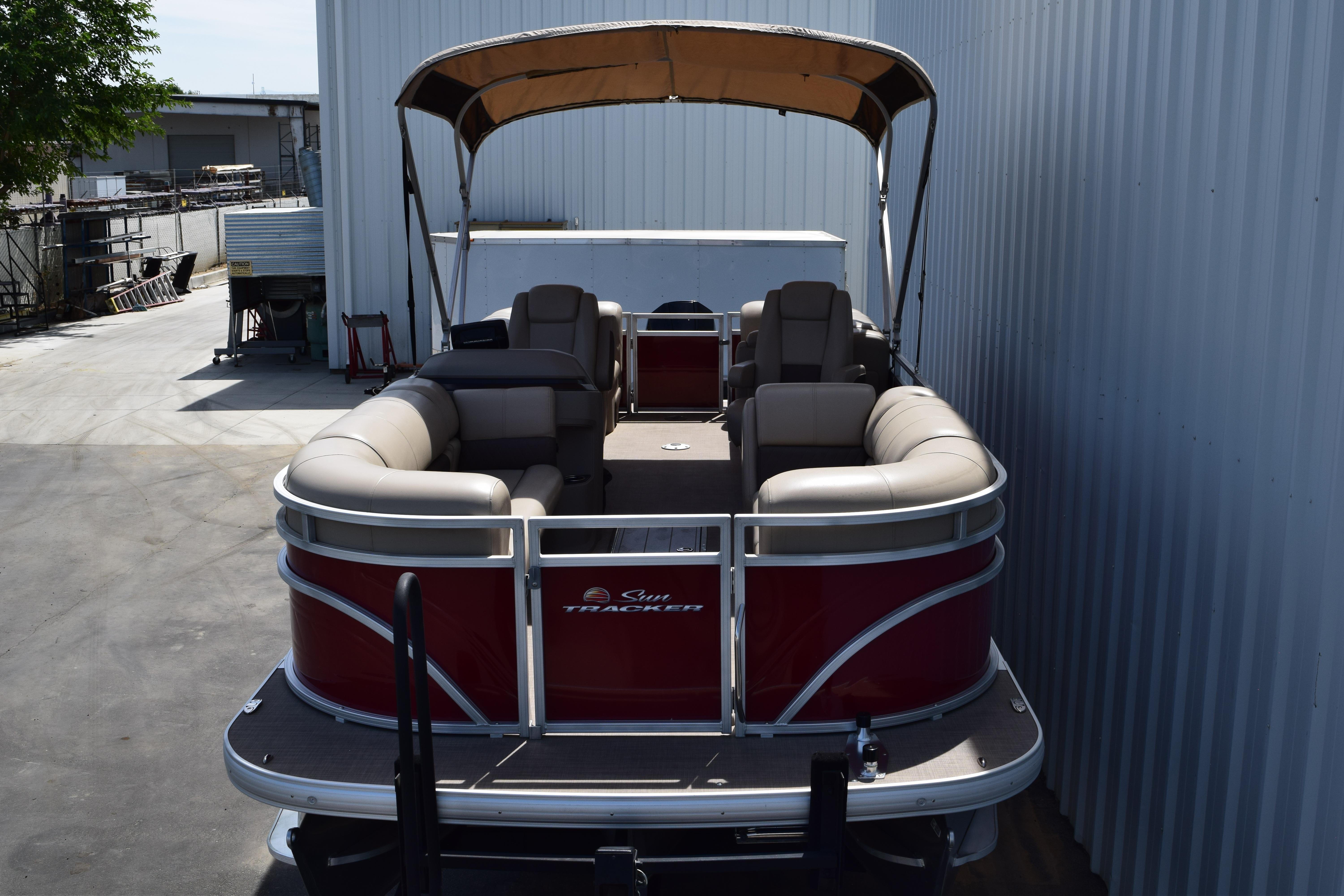 2025 Sun Tracker Party Barge 22 XP3 pontoon boat with canopy, docked beside a building.