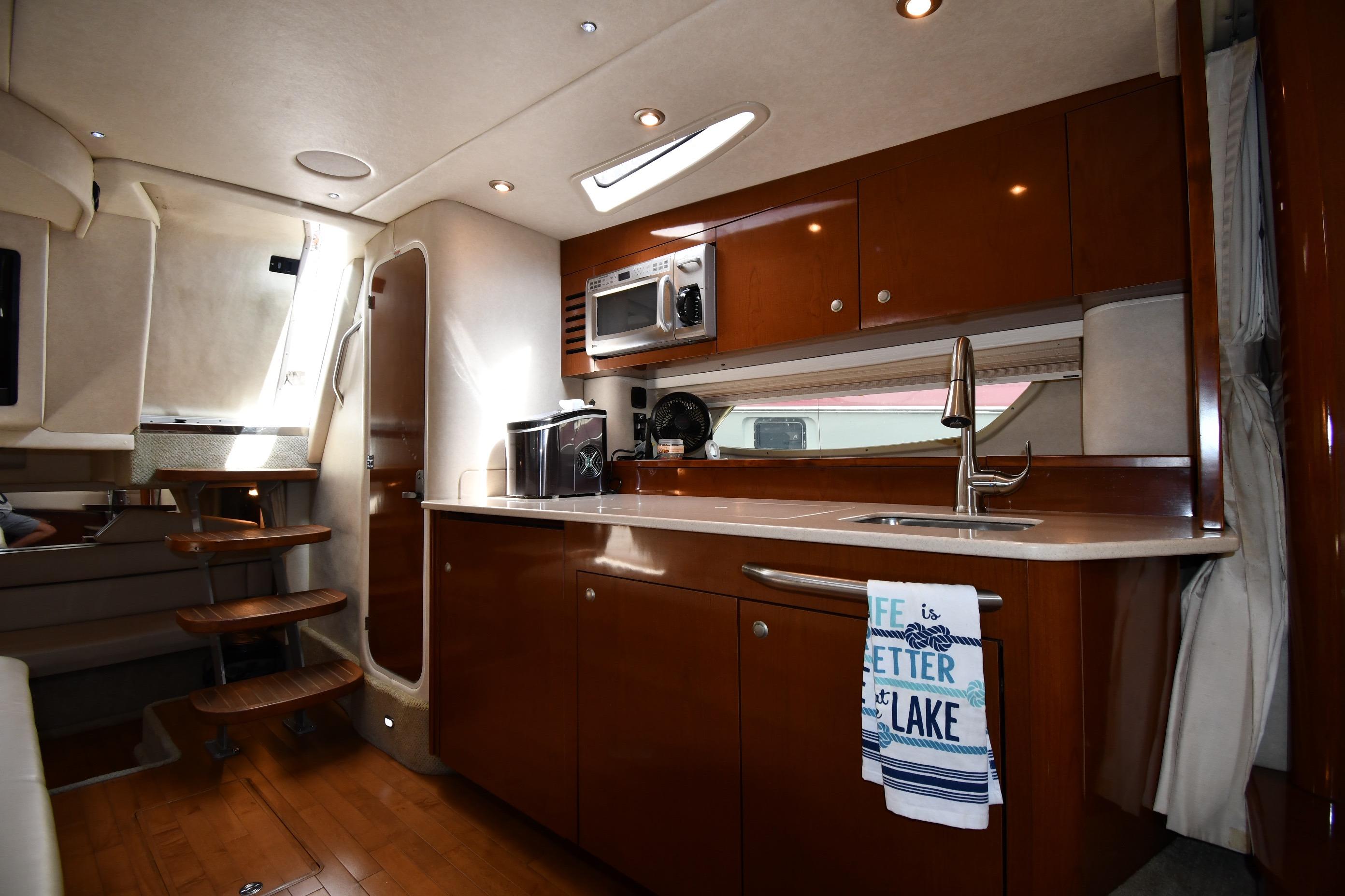 Interior of 2008 Sea Ray Sundancer 350 yacht kitchen with wooden cabinetry and modern appliances.