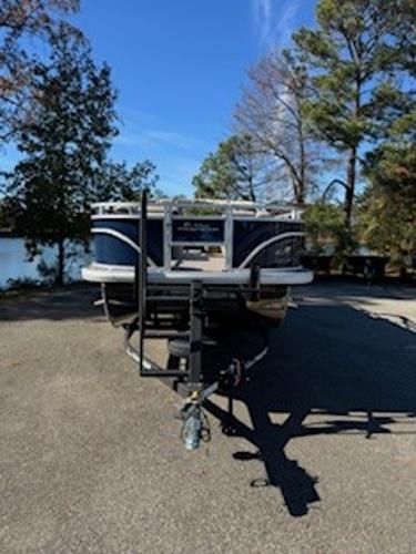 2025 Sun Tracker Fishin' Barge 22 DLX on trailer, forest background.