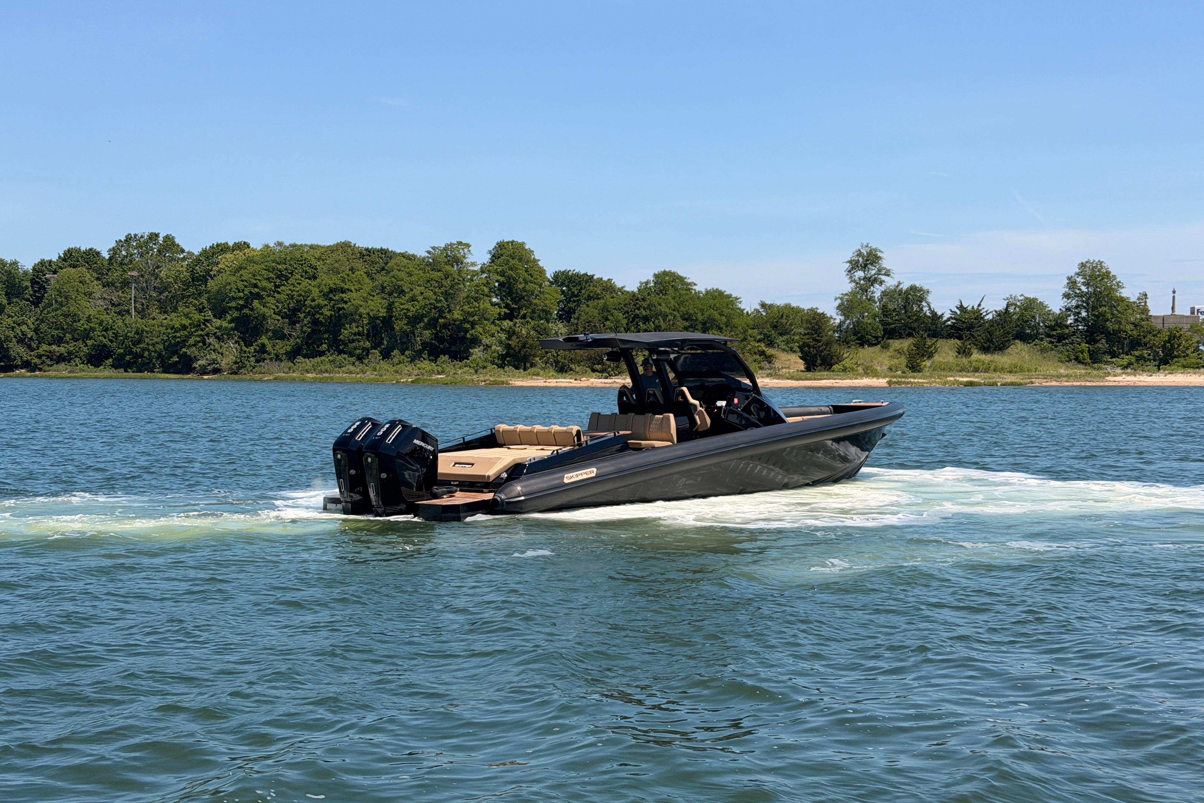 2023 Skipper-BSK 42NC boat cruising on a scenic lake with lush green shoreline.