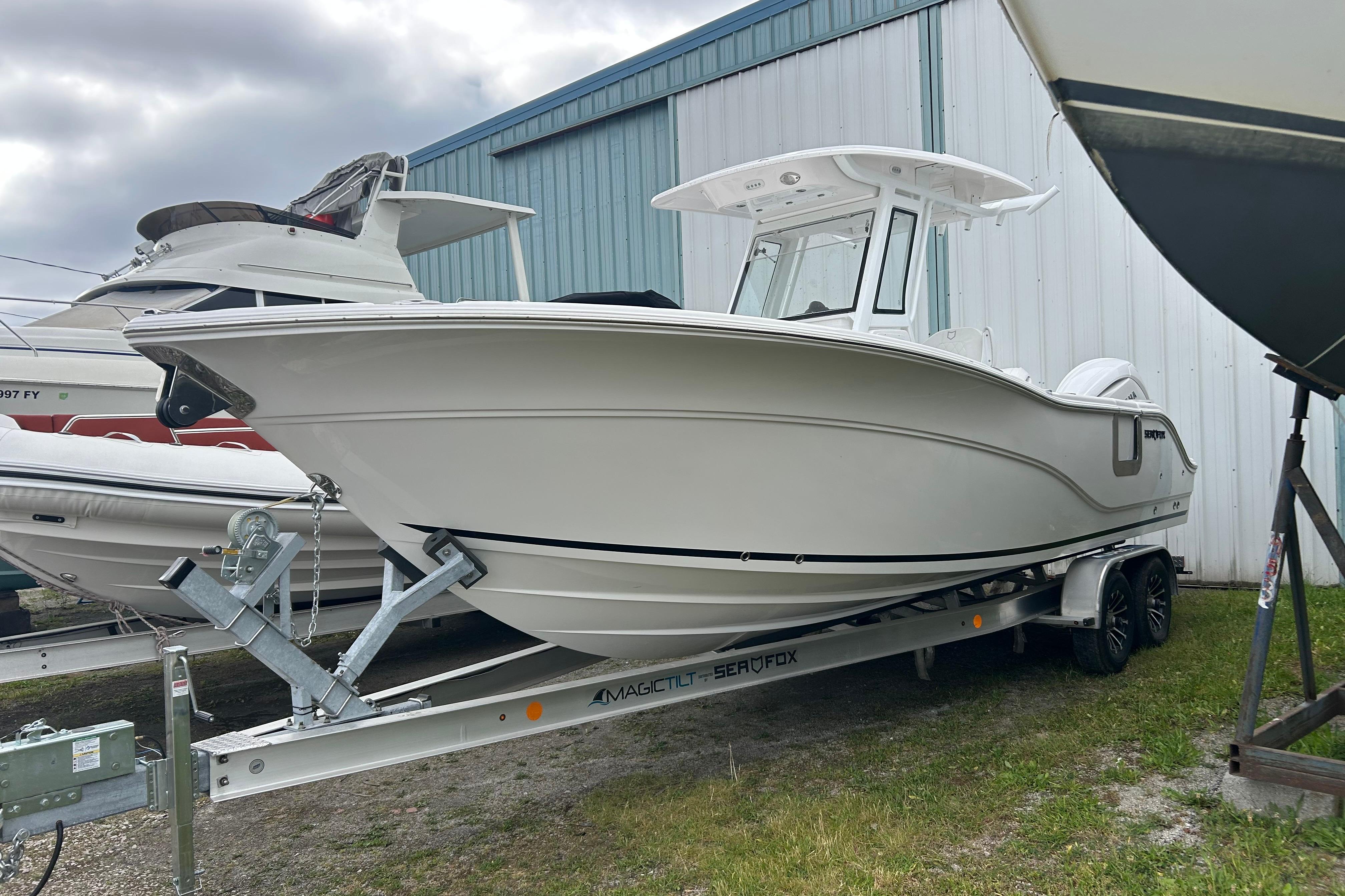 2026 Sea Fox 268 Commander boat on trailer, parked near a blue and white building.