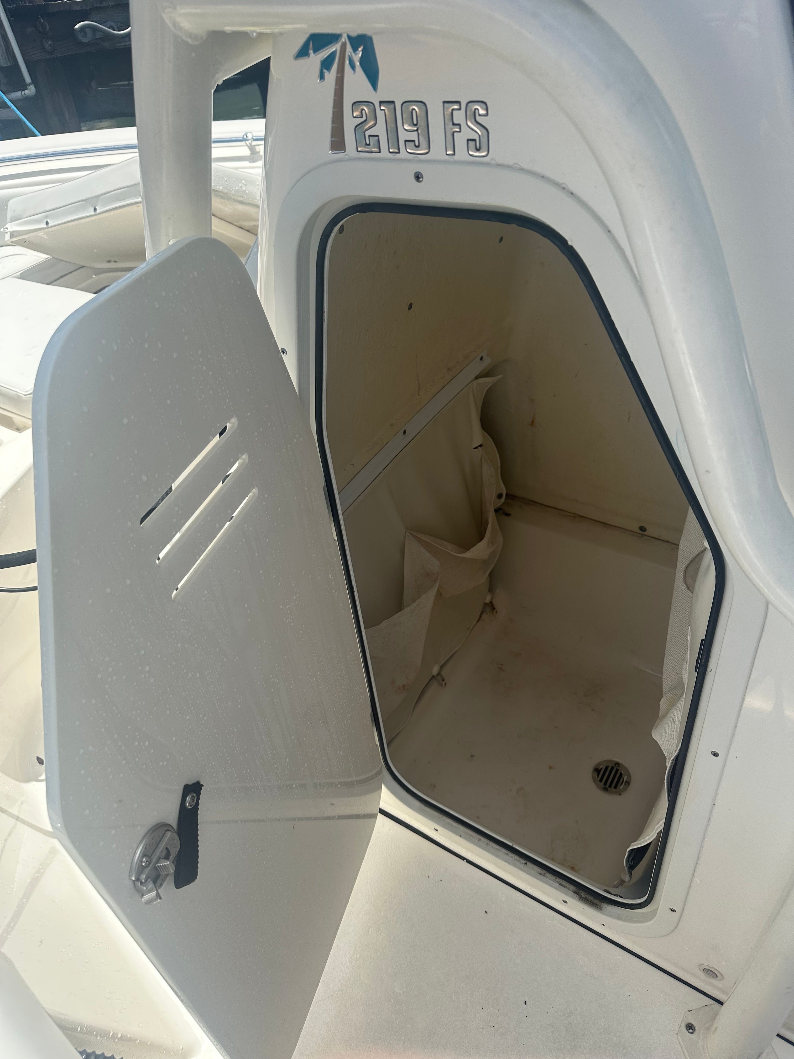 An open door on a boat reveals a small storage compartment.
