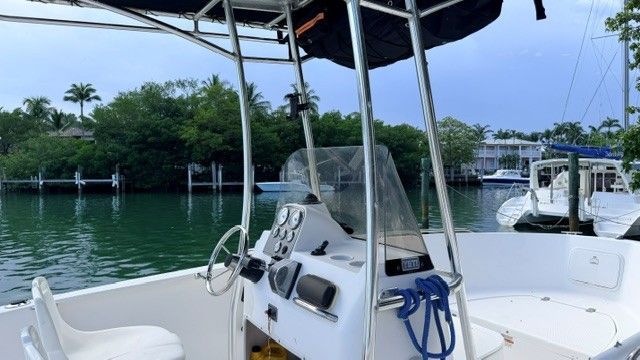 A 2004 Wellcraft 180 Fisherman on calm water with lush greenery in the background.