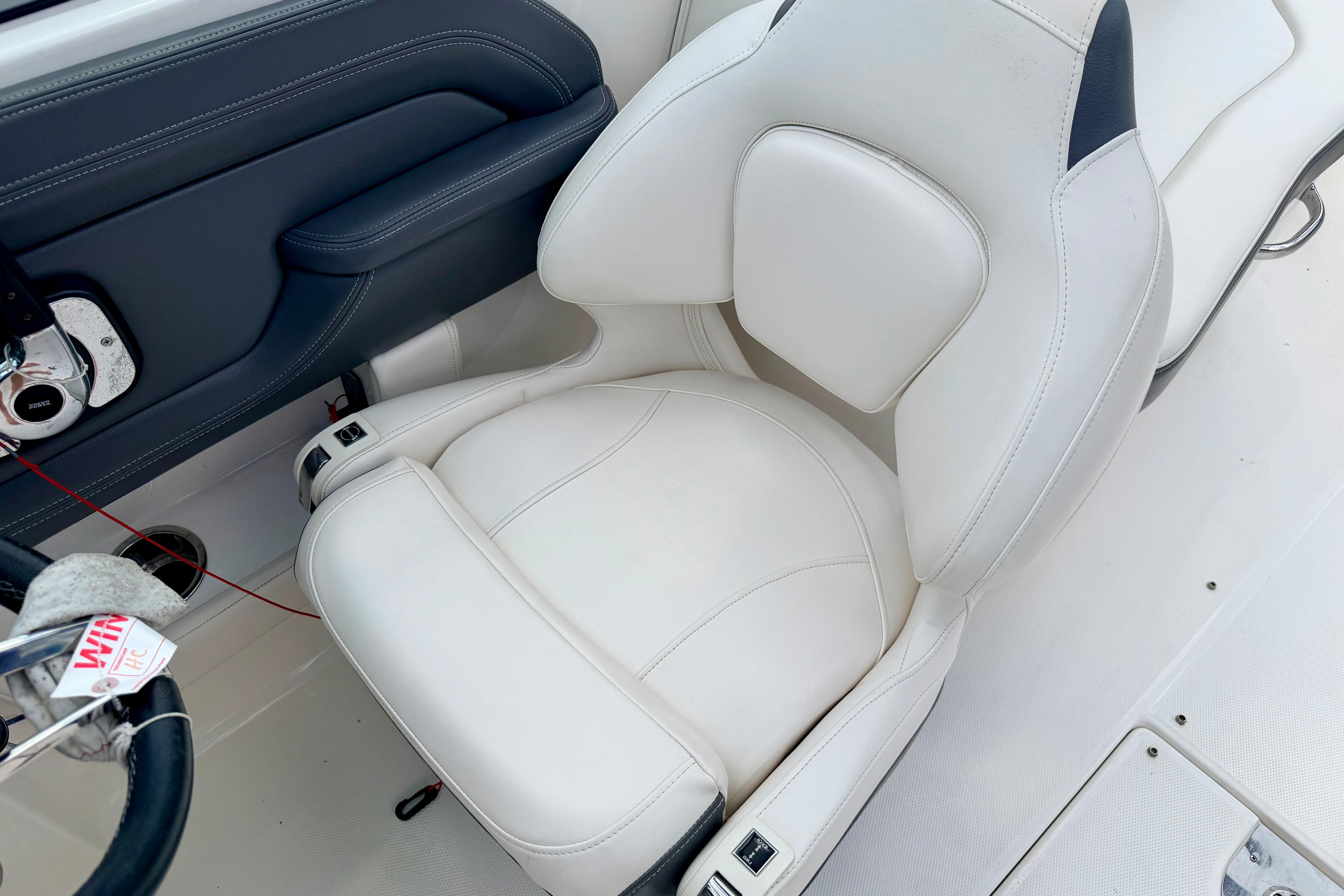 2015 Chaparral Sunesta 264 boat interior with white cushioned seat and steering wheel.