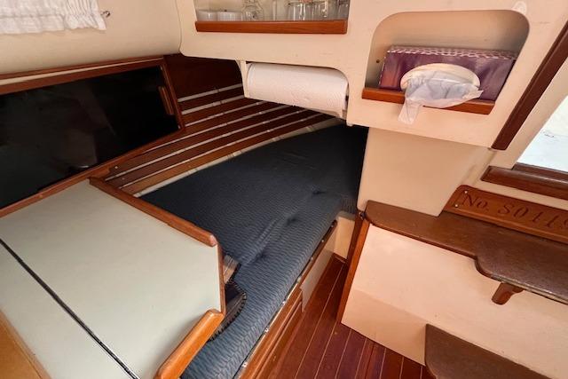 Interior of 1984 Bayfield 29 sailboat with cozy sleeping area and wooden accents.