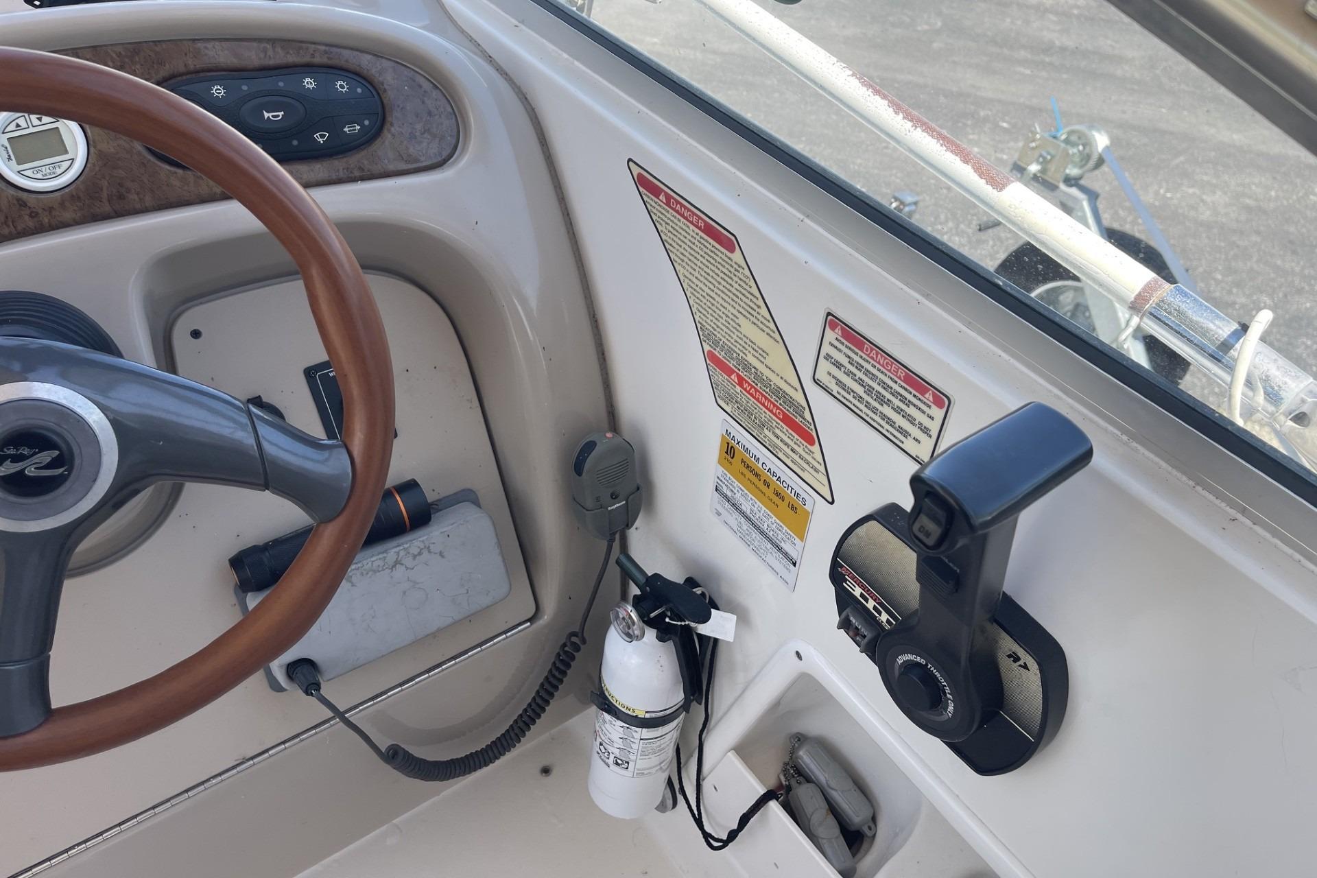 Steering console of a 2000 Sea Ray Sundancer 260 boat with controls and safety labels.