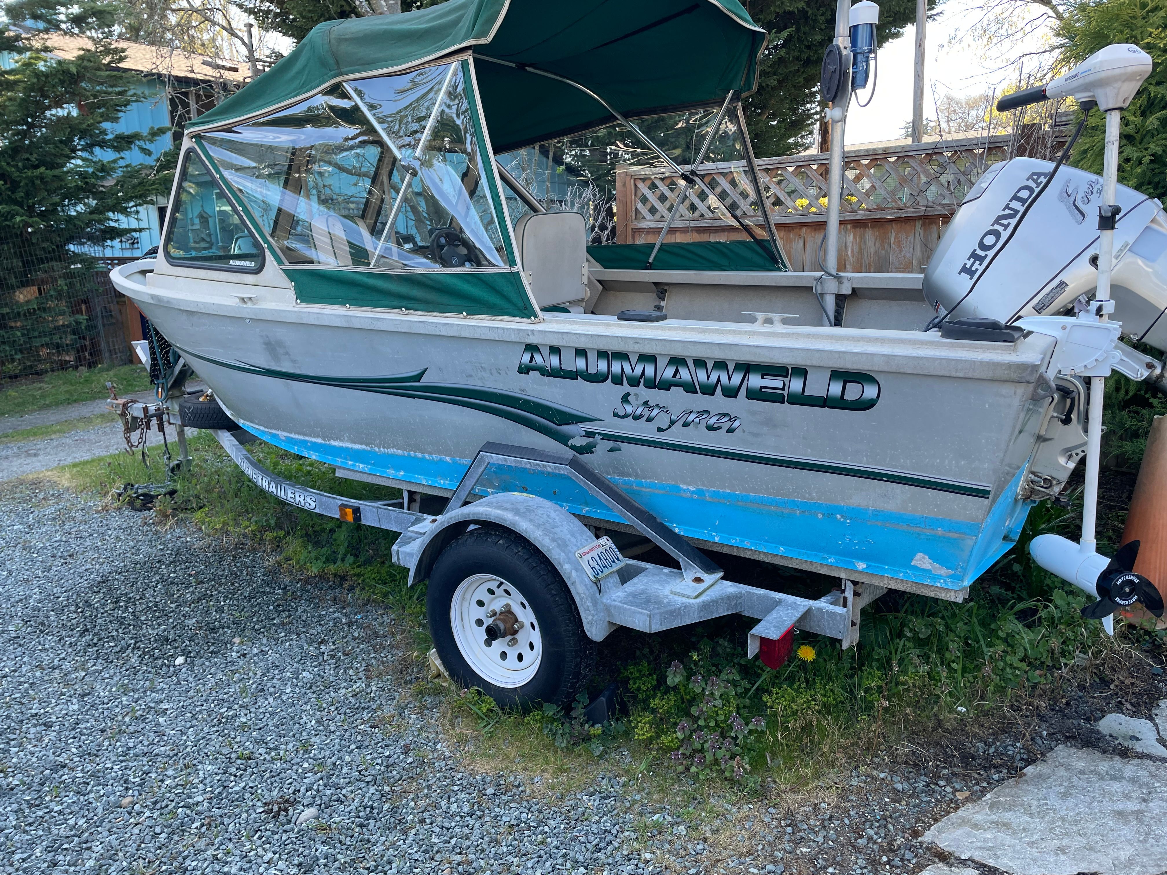A 2001 Alumaweld Stryker boat on a trailer, surrounded by trees.