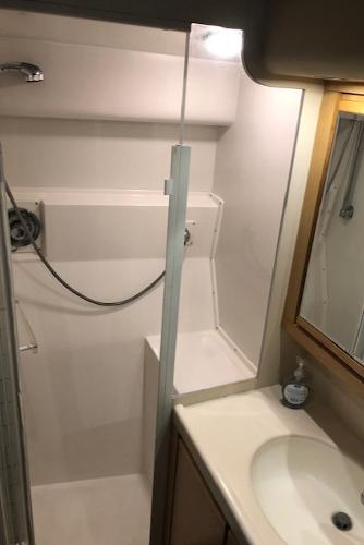 1997 Bertram Convertible bathroom with shower, sink, and mirror.