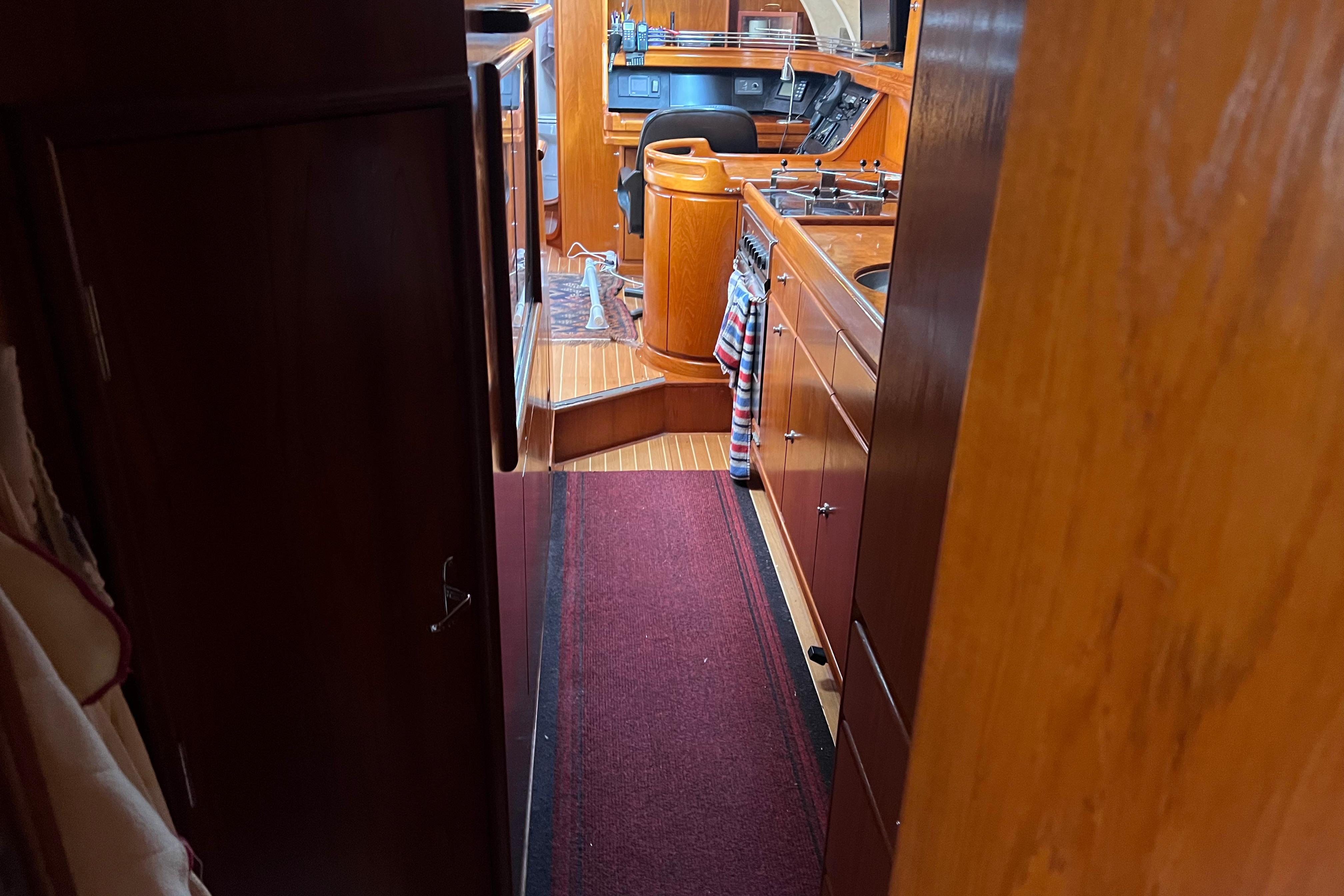 Interior view of 1990 Trintella 49A yacht, featuring wooden cabinetry and a compact kitchen area.