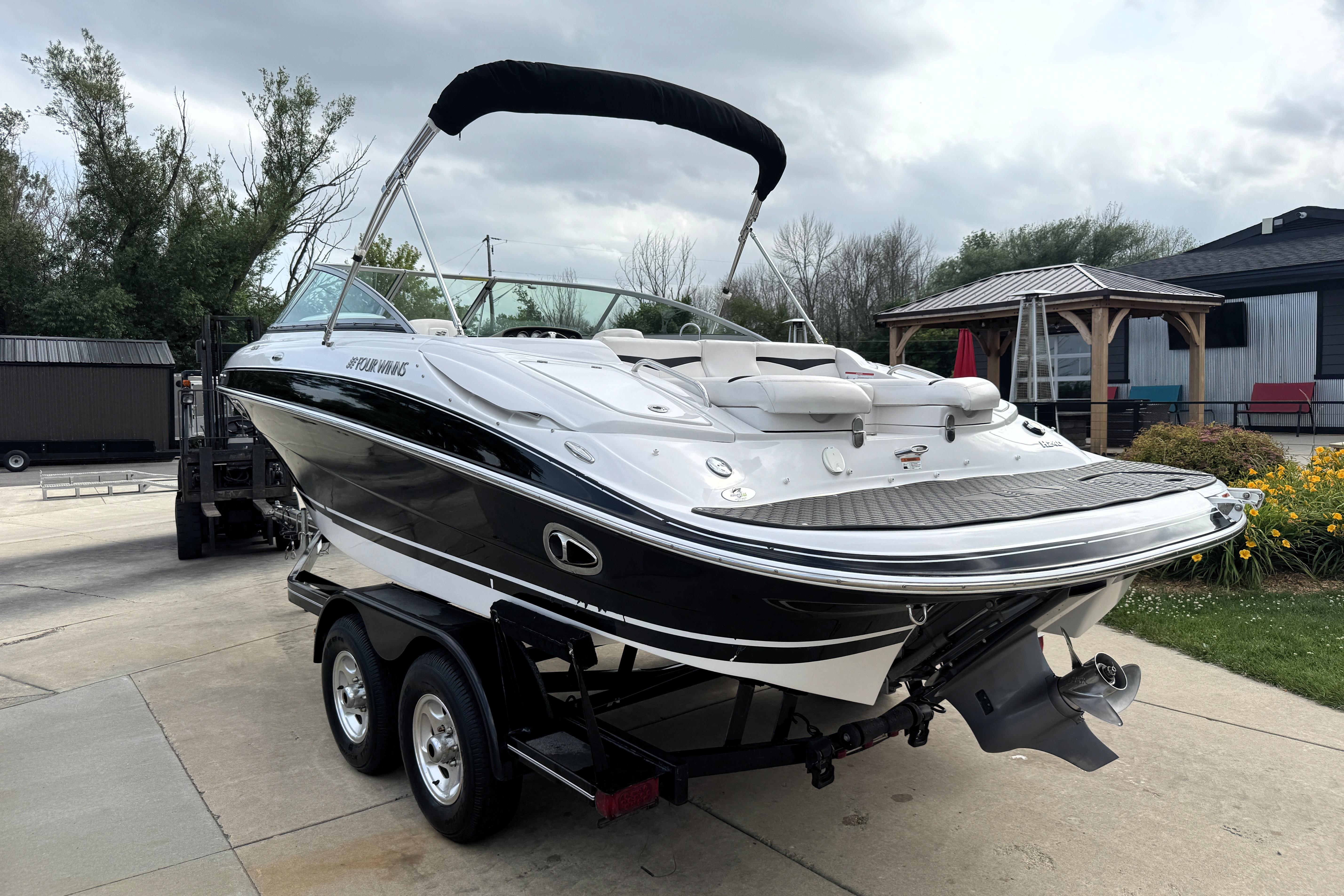 2008 Four Winns H240 boat on trailer, parked outdoors with overcast sky.
