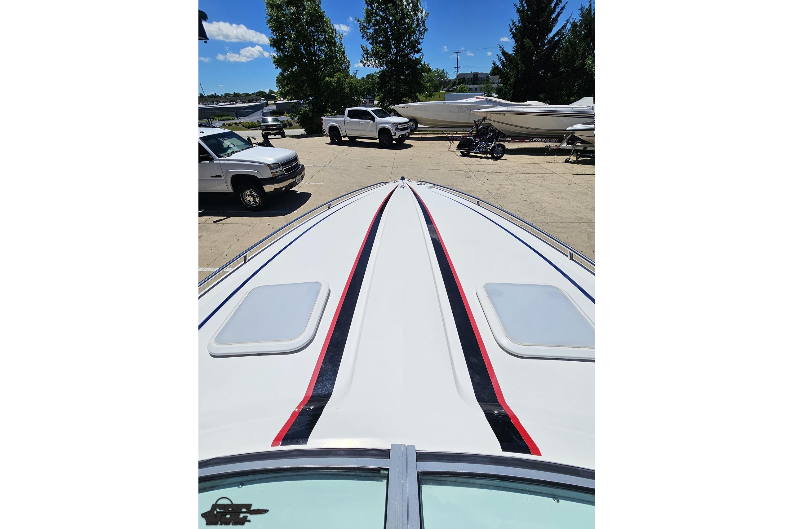 2005 Formula 271 FASTech boat, white with red and black stripes, parked near vehicles.