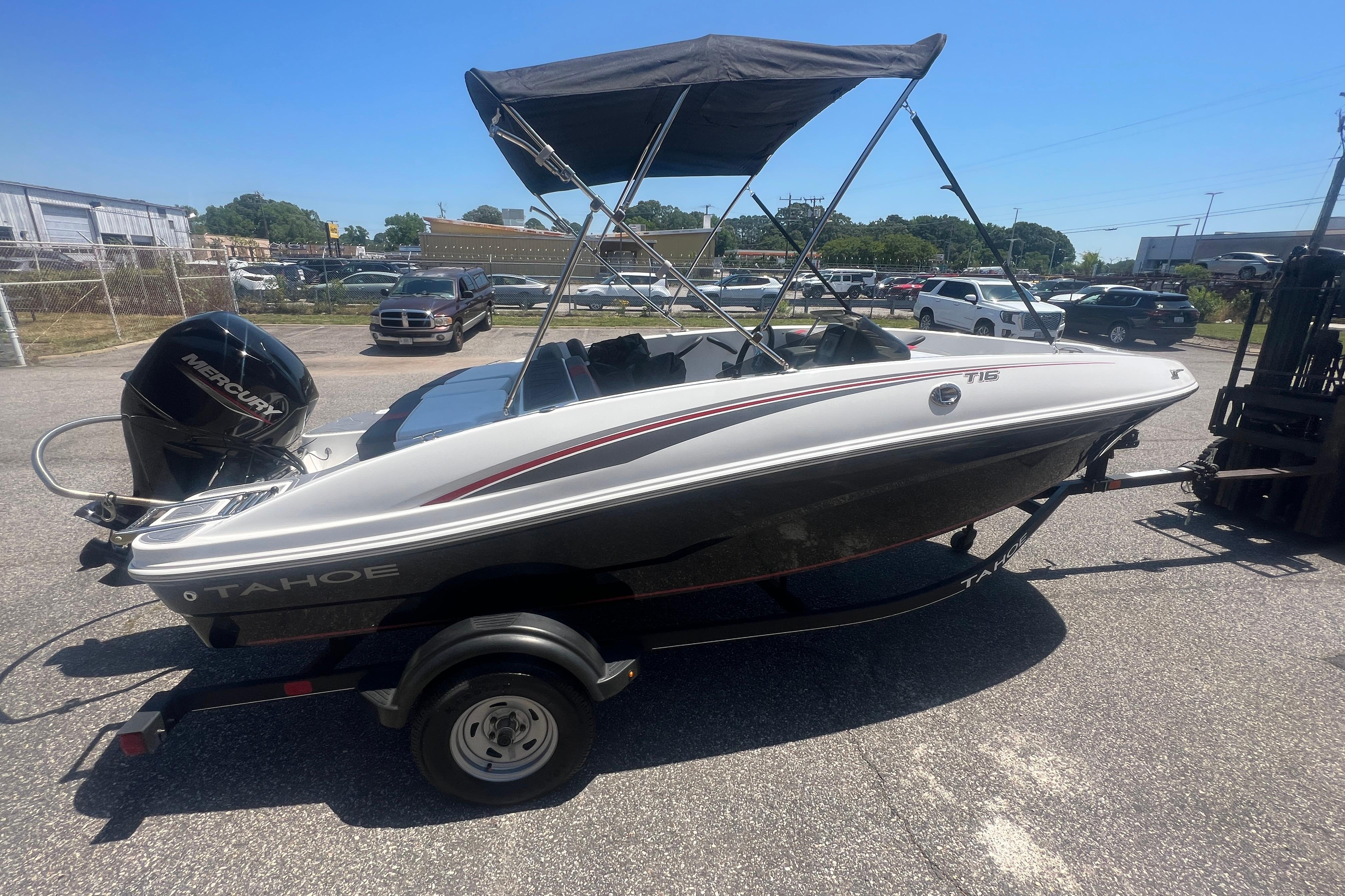 2023 Tahoe T16 boat with Mercury engine on trailer, parked outdoors under clear sky.