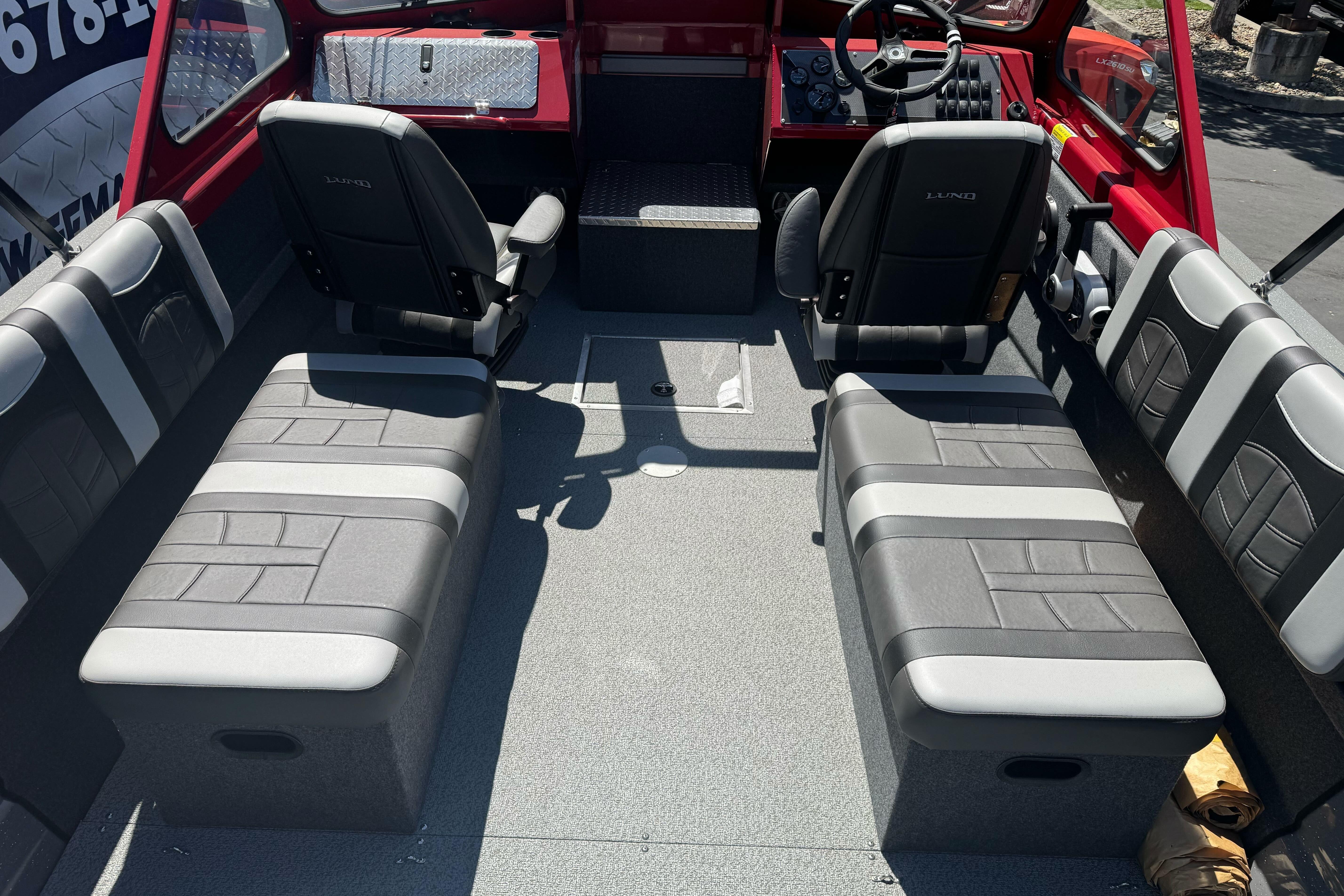 Interior of 2026 Lund 210 Heavy Gauge boat with gray seating and red dashboard.