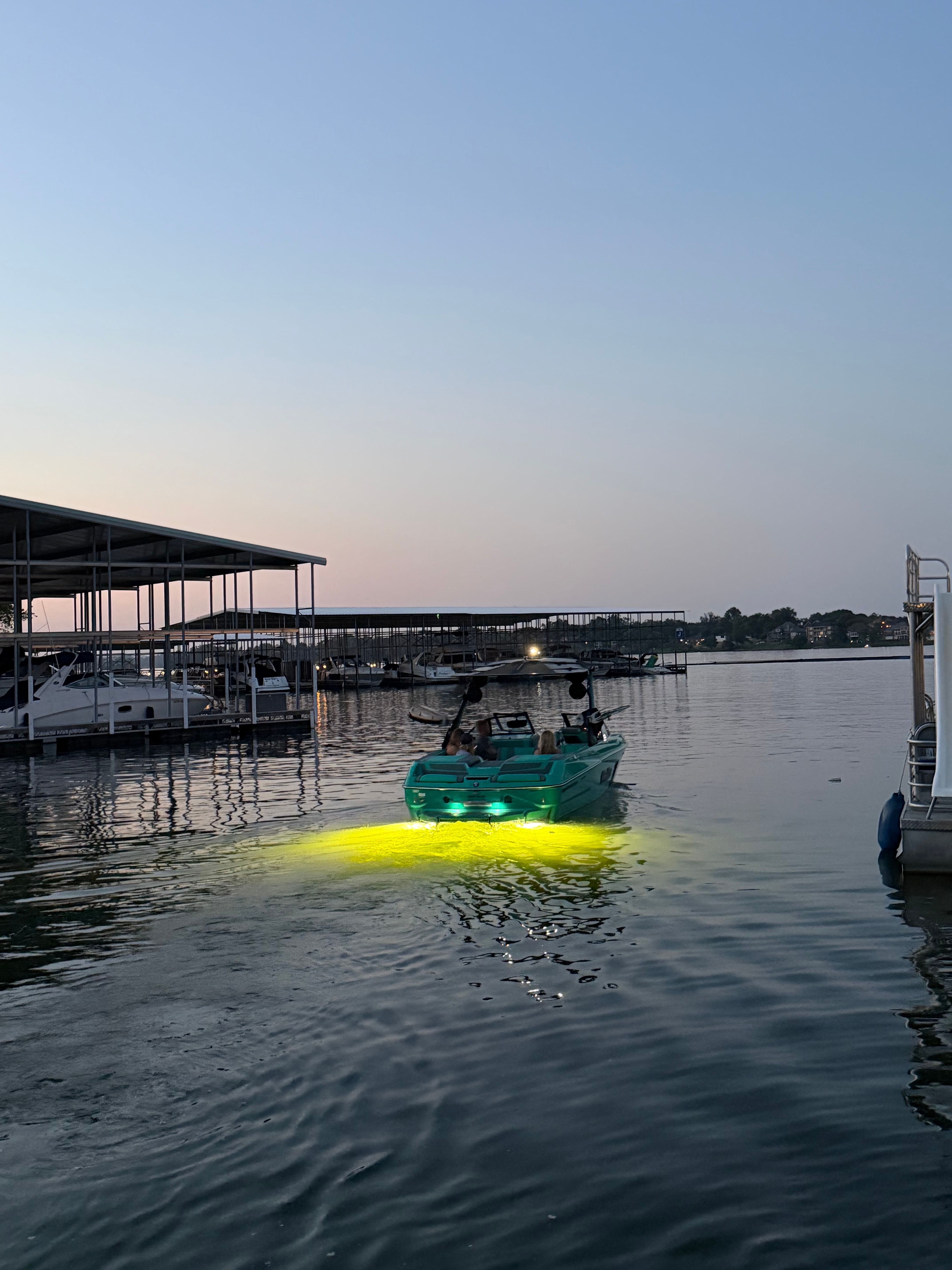 A 2023 Malibu Wakesetter 24 MXZ on the water at dusk with glowing lights.