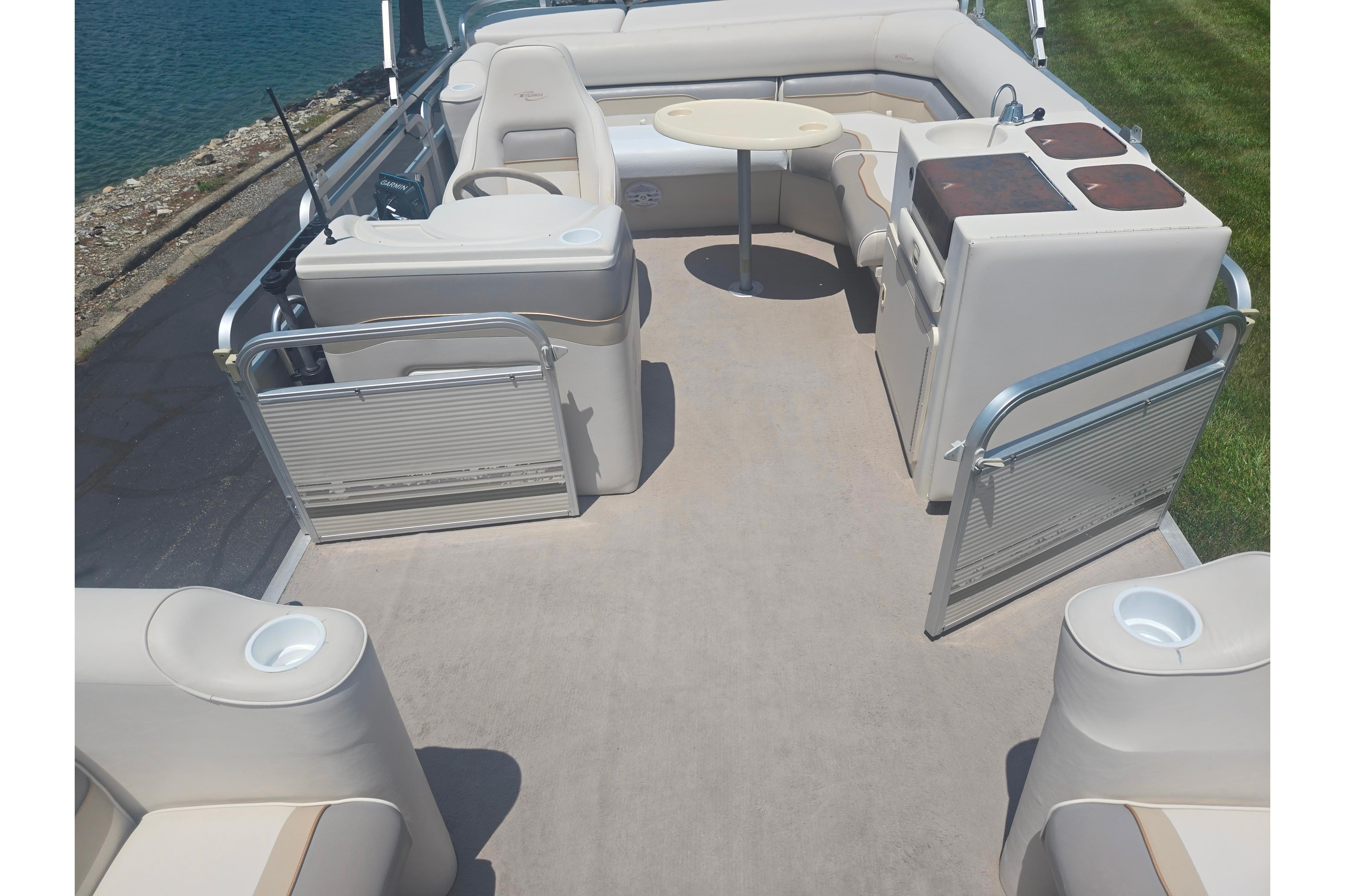 2000 Sylvan 824 Elite Cruise boat interior with seating and table, docked by the water.